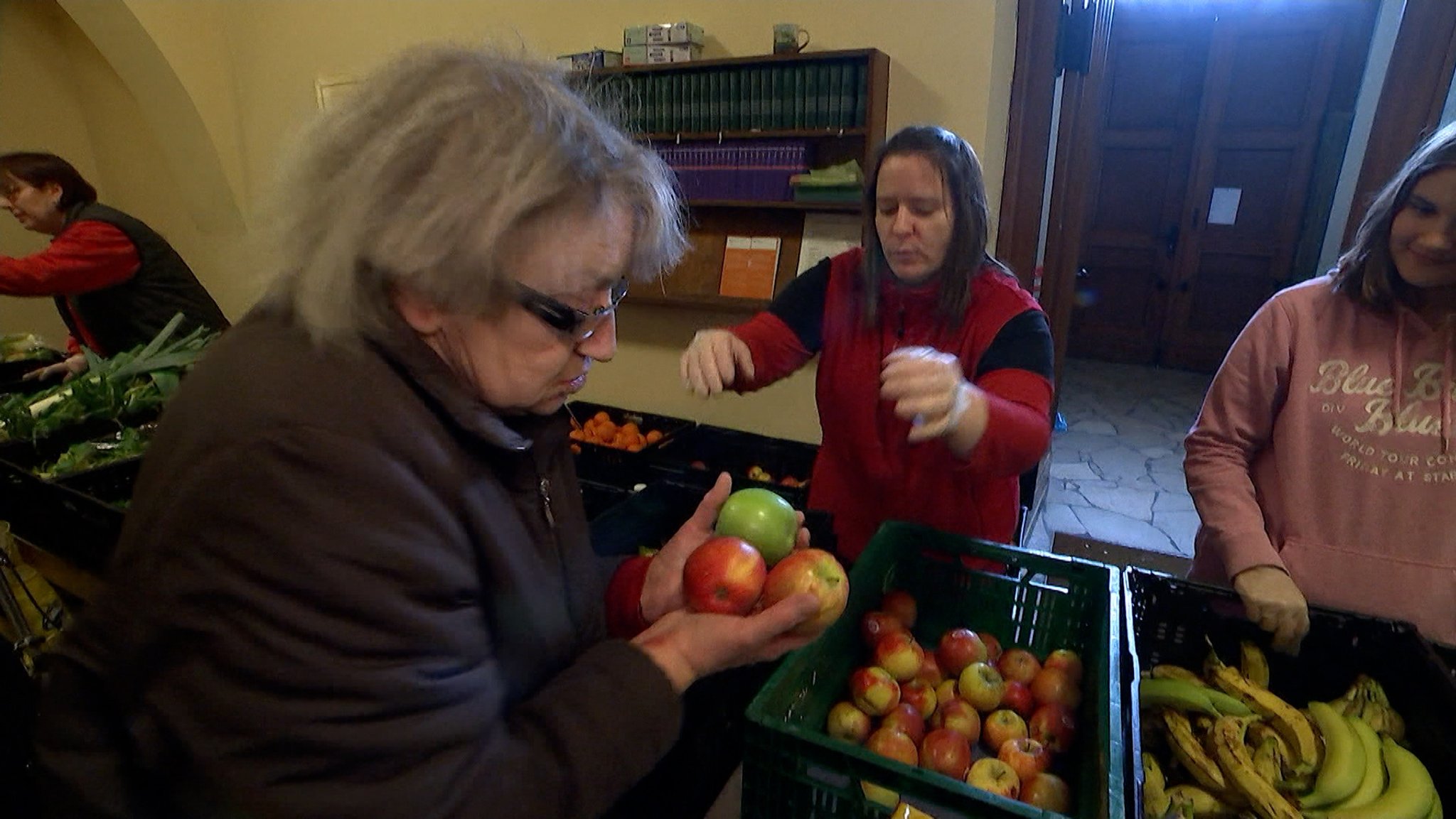 Mitarbeiter bei der Tafel geben Obst an Bedürftige aus. 