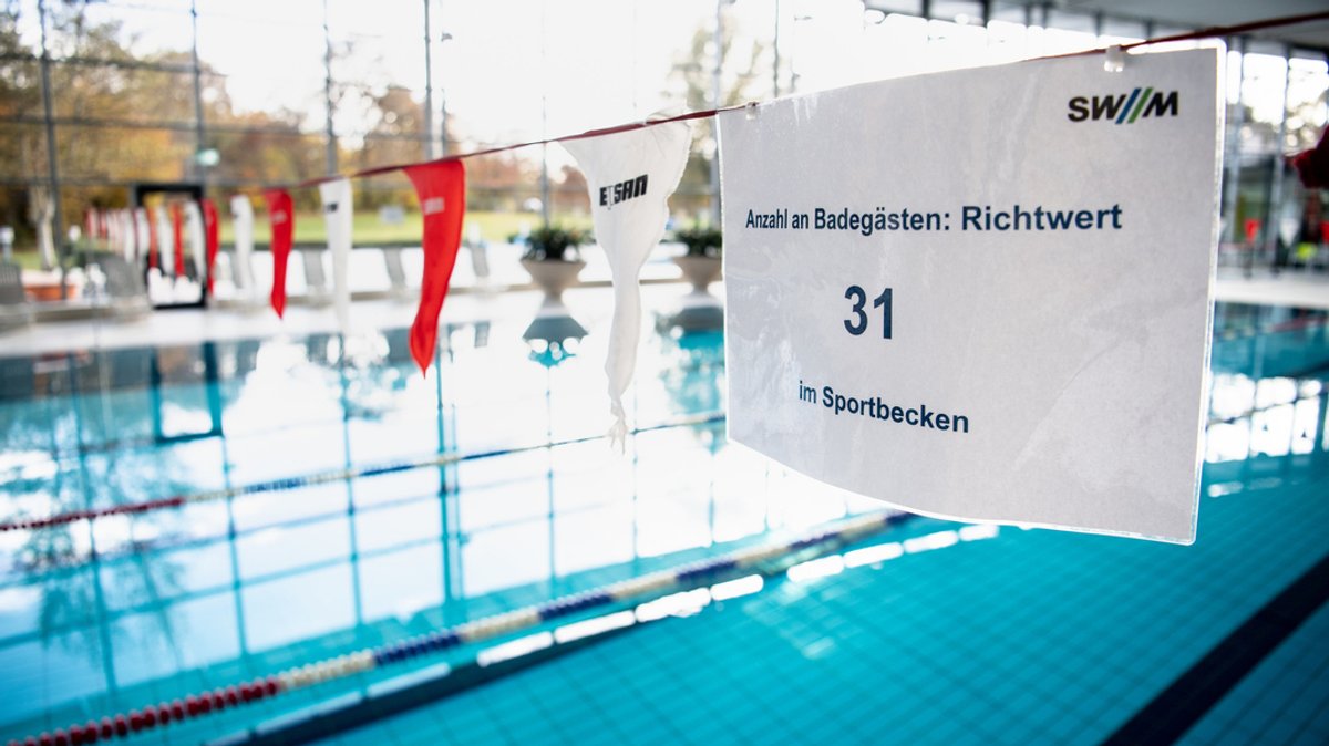 Ein Schwimmbecken ist mit einem Schild versehen: "Anzahl an Badegästen: Richtwert 31 Sportbecken" steht dort. 