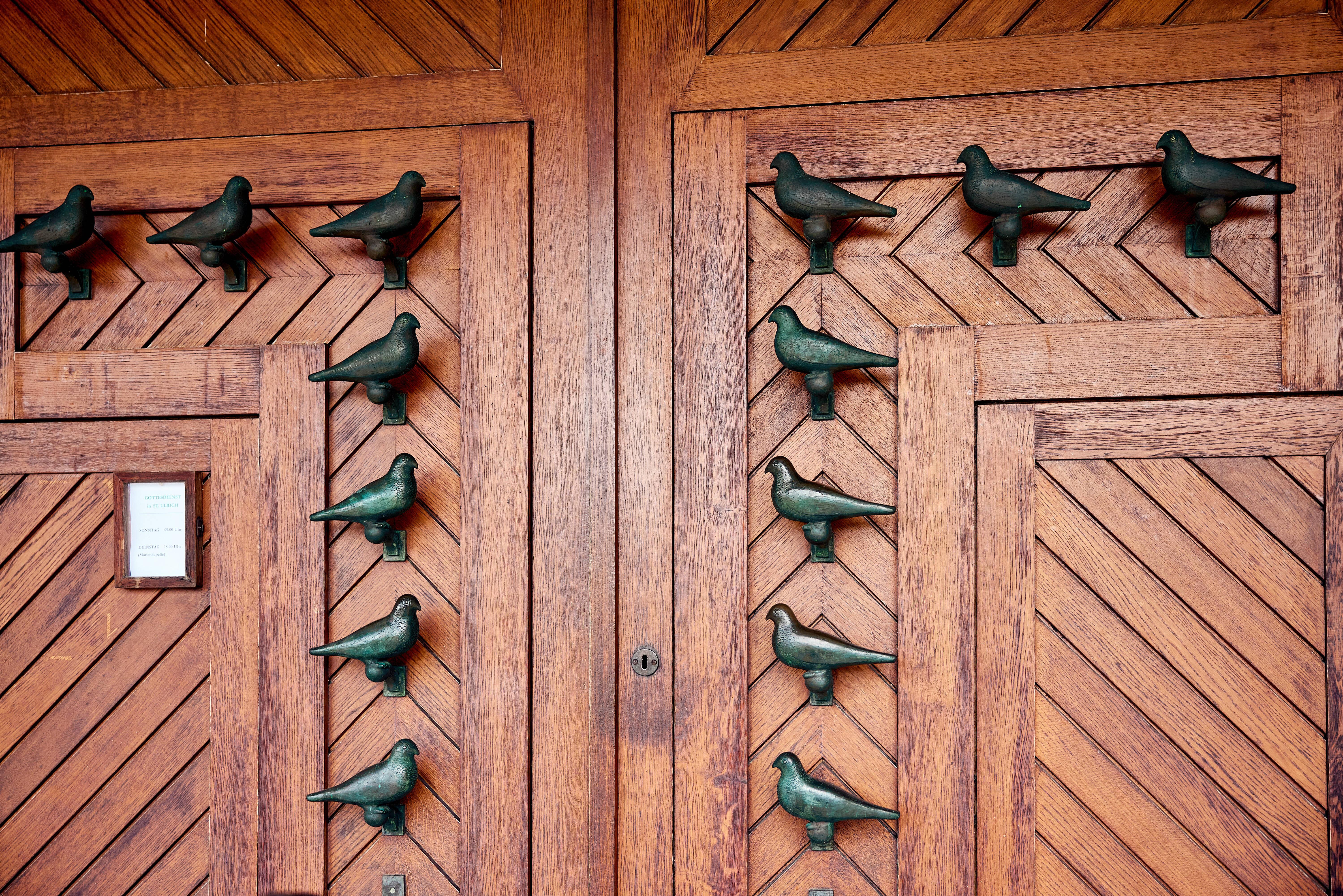 Die Eingangstür der katholischen Kirche St. Ulrich in Augsburg mit Tauben-Motiven