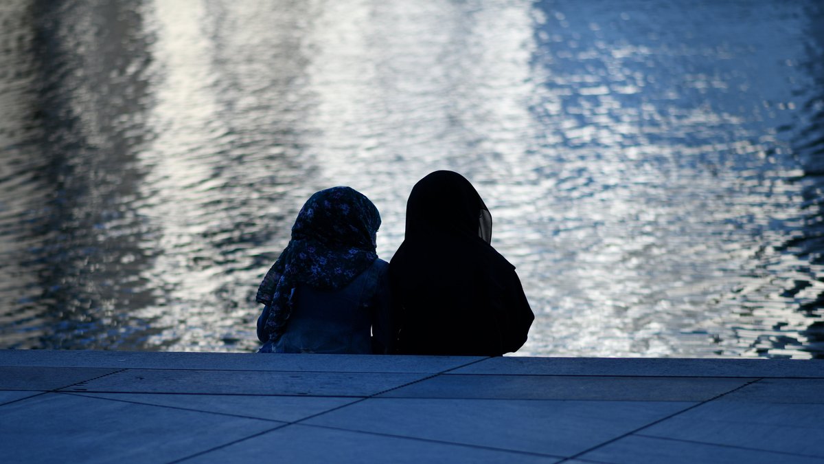 Zwei Frauen mit Kopftuch als Silhouette am Spree Ufer, aufgenommen am 07.06.2021 in Berlin.