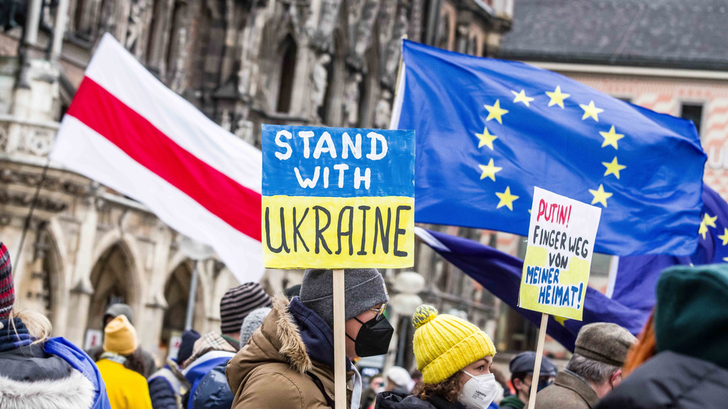 06.02.22: Gelb-blaues Schild mit der Aufschrift "Stand with Ukraine" bei einer Demonstration in München.