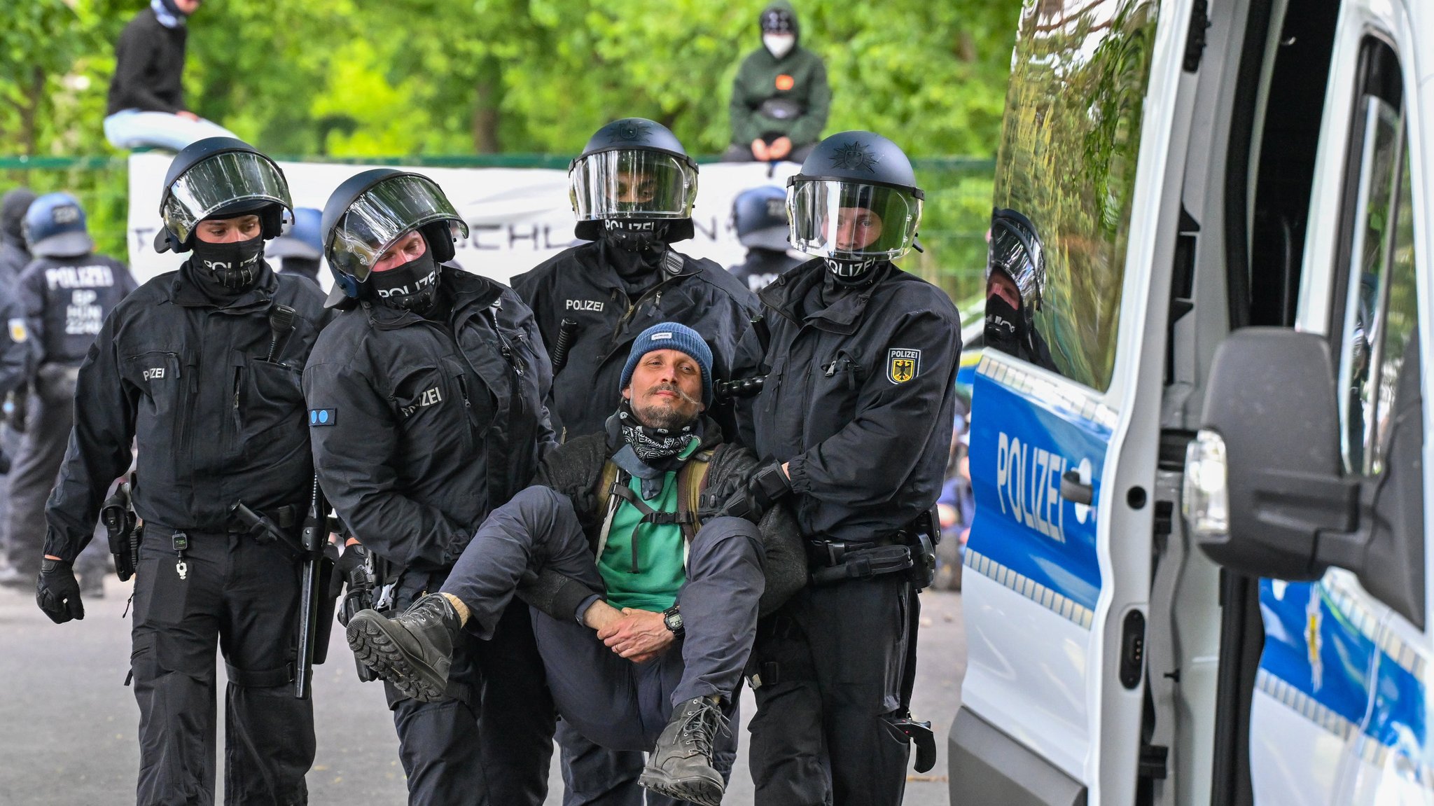 Polizisten räumen eine Blockade von Aktivisten an der Zufahrt zum Flugplatz Neuhardenberg. Auf dem Gelände des Flugplatzes werden Fahrzeuge von Tesla zwischengelagert, die im Werk in Grünheide produziert wurden.