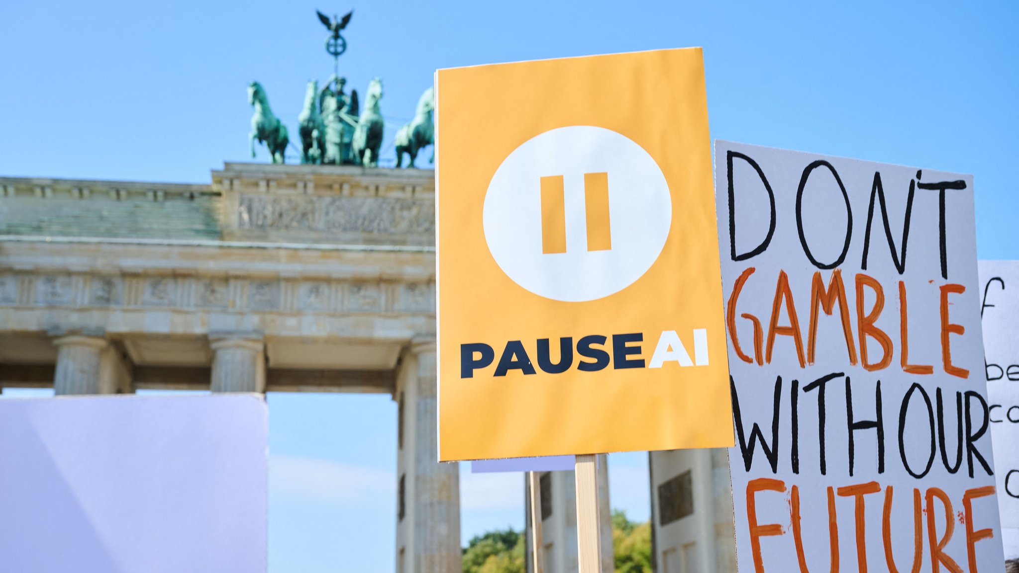 15.09.2026, Berlin: Vor dem Brandenburger Tor stehen Demonstranten mit Plakaten wie „Pause-KI“ oder „Dont Gamble with your future“. Die Demonstration der Initiative PauseAI ist gegen den „KI-Kontrollverlust“ und fordert die Bundesregierung auf, sich für ein internationales KI-Moratorium einzusetzen. Foto: Annette Riedl/dpa +++ dpa-Bildfunk +++