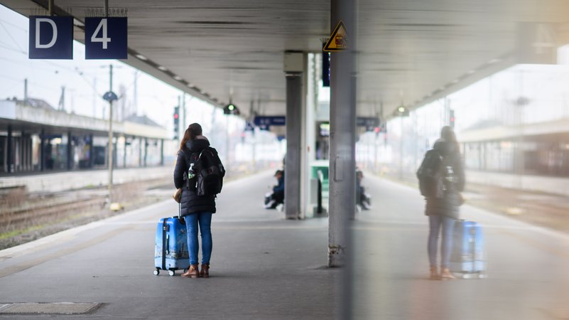 Eine Frau wartet mit einem Koffer am Bahnsteig | Bild: picture alliance/dpa | Julian Stratenschulte Eine Frau wartet mit einem Koffer am Bahnsteig