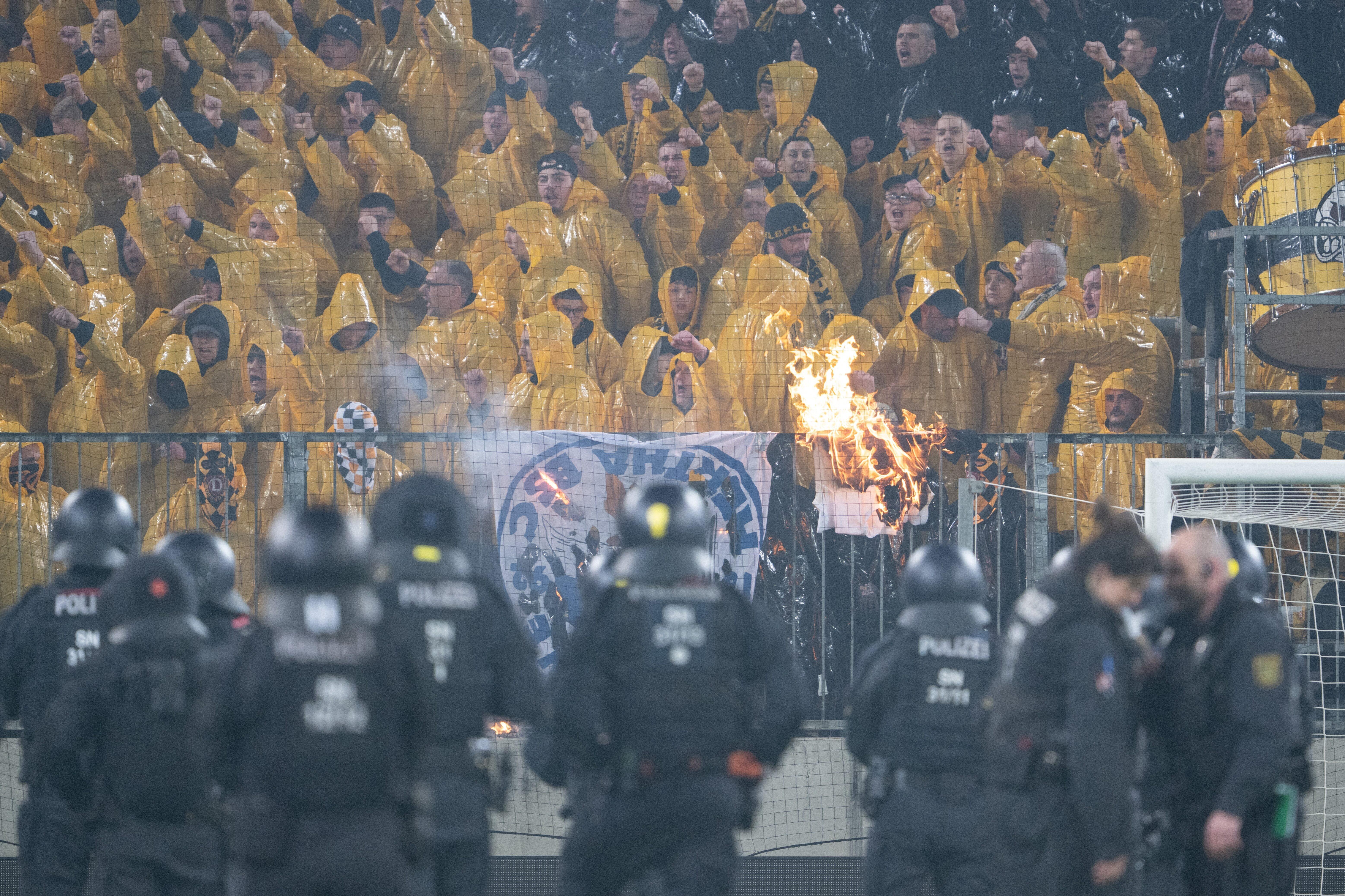 Archivbild: Polizisten stehen während einer Spielunterbrechung im Stadion auf dem Spielfeld vor dem K-Block mit den Fans von Dynamo Dresden.