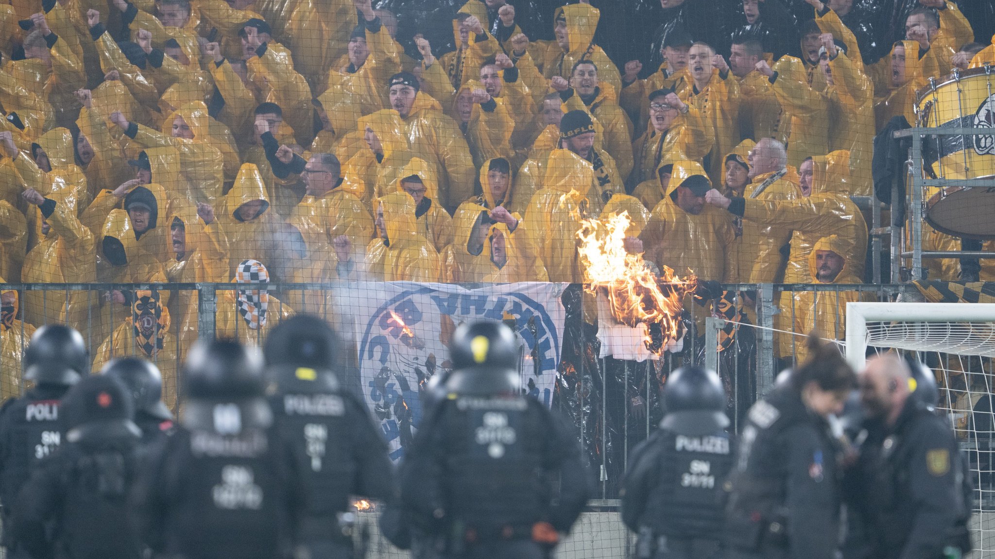 Archivbild: Polizisten stehen während einer Spielunterbrechung im Stadion auf dem Spielfeld vor dem K-Block mit den Fans von Dynamo Dresden.
