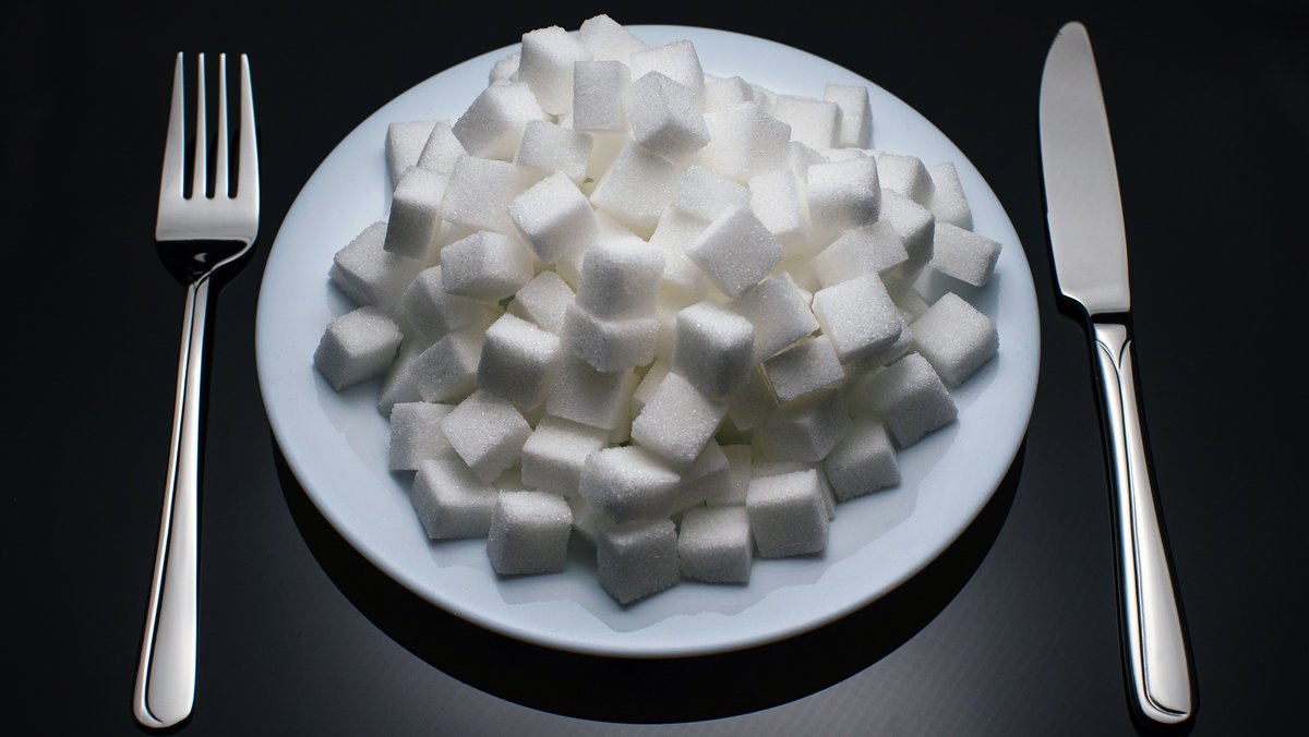 Teller mit Zuckerwürfeln und Besteck (Symbolbild: Fettleibigkeit)