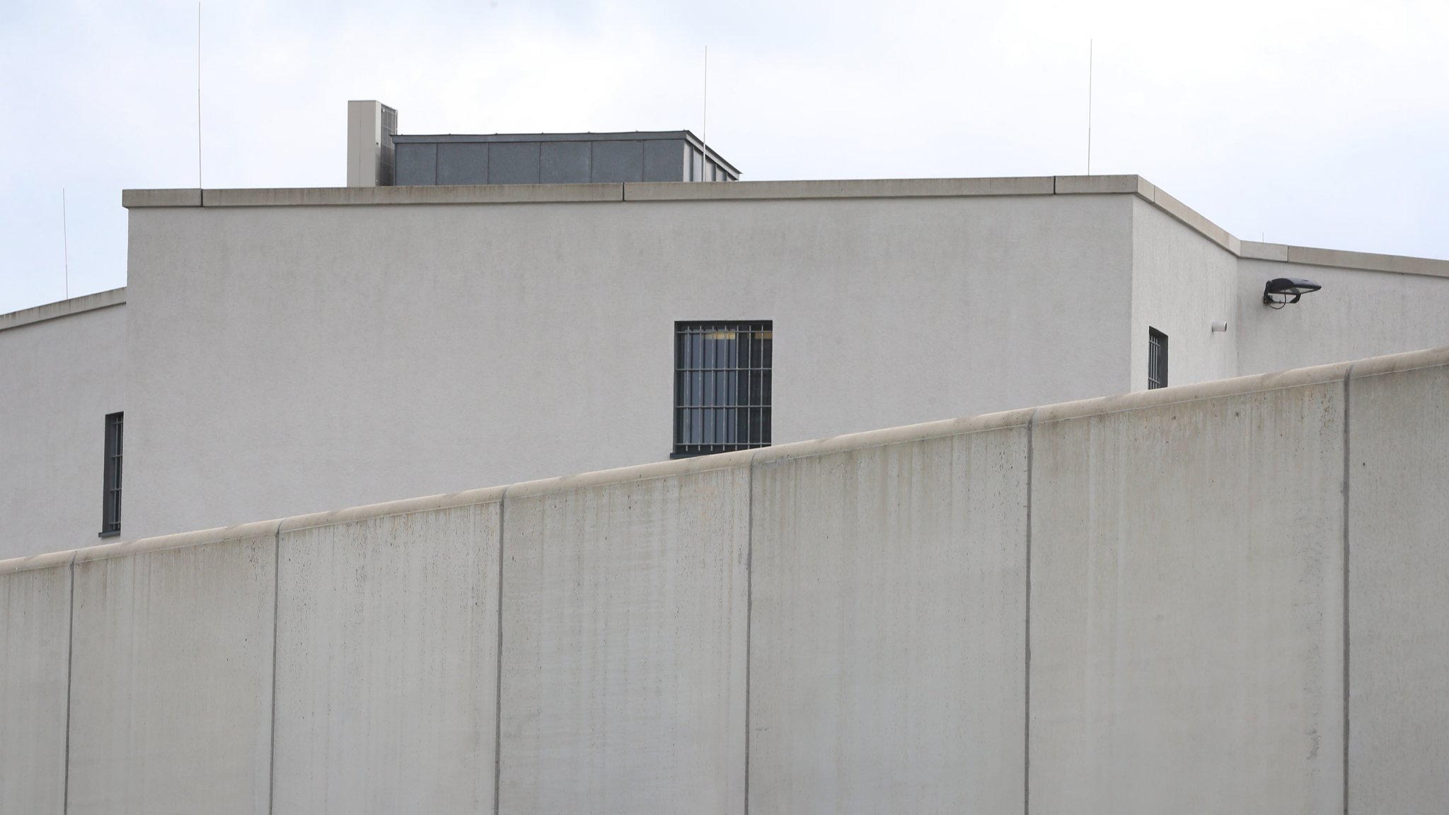 Vergitterte Fenster sind hinter einer Mauer der Justizvollzugsanstalt Gablingen zu sehen.