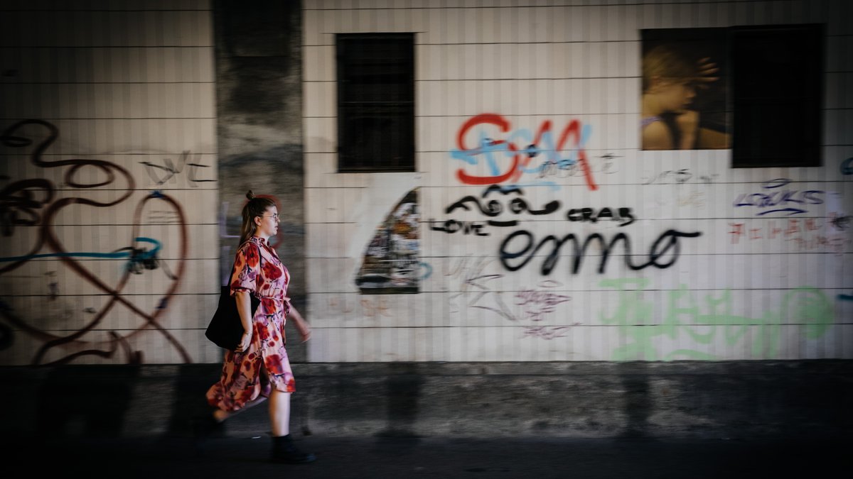 Eine junge Frau läuft durch eine mit Graffittis beschmierte Unterführung.