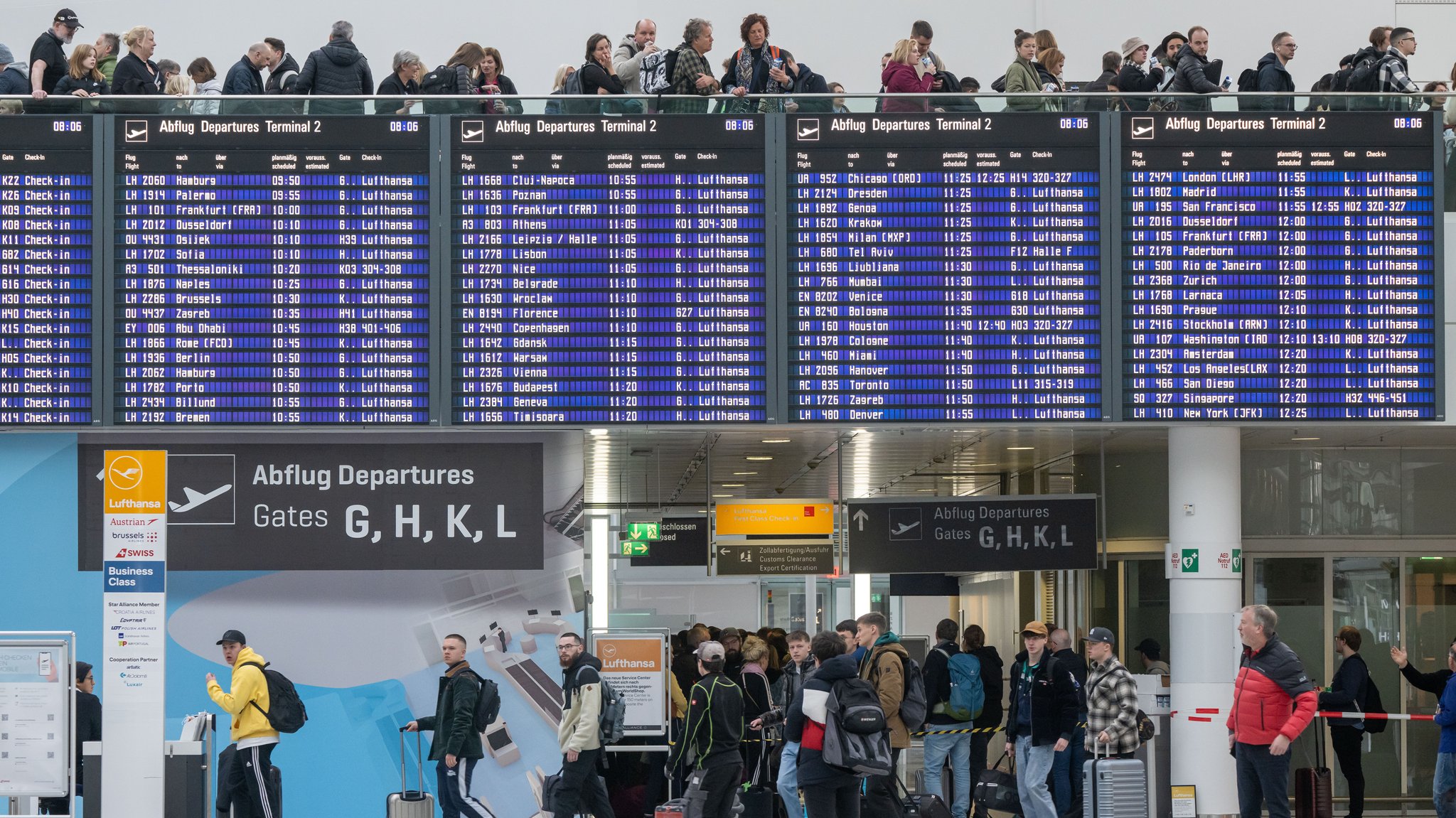 Menschenschlangen bestehen mit ihrem Reisegepäck dicht gedrängt um die Flugtafel am Münchner Flughafen.