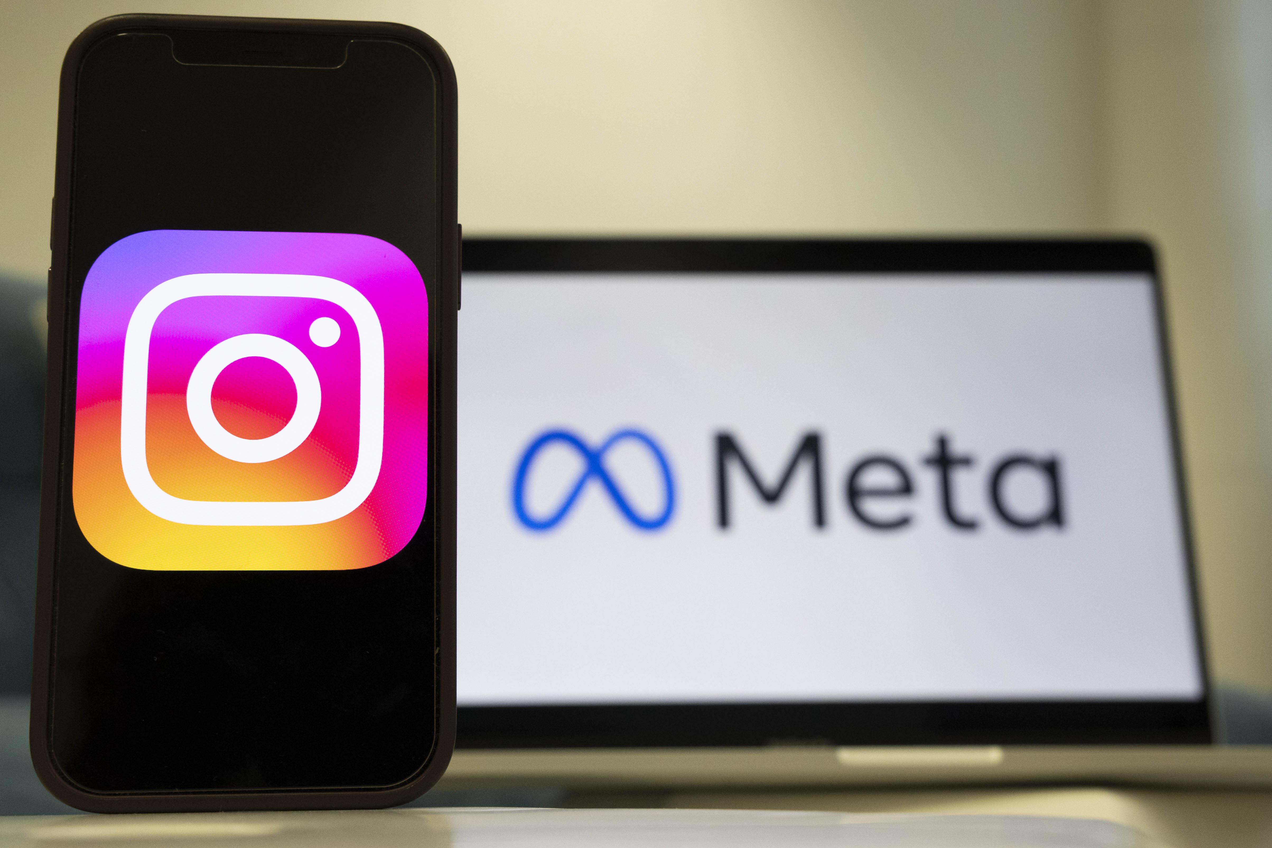 Instagram-Logo auf einem Smartphone, dahinter ein Laptop mit dem Meta-Logo.