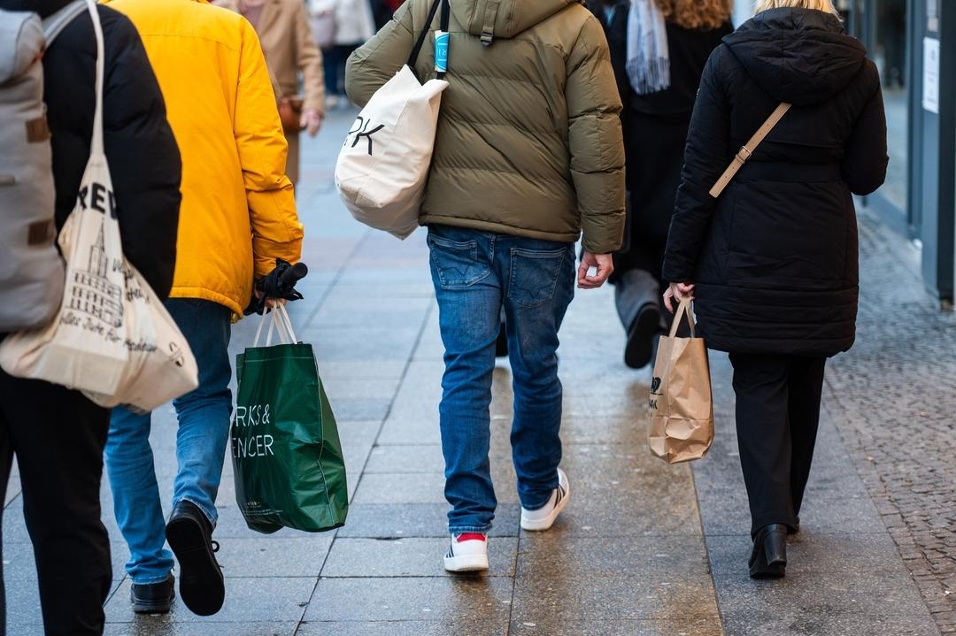 Menschen tragen verschiedene Einkaufstüten (Symbolbild).