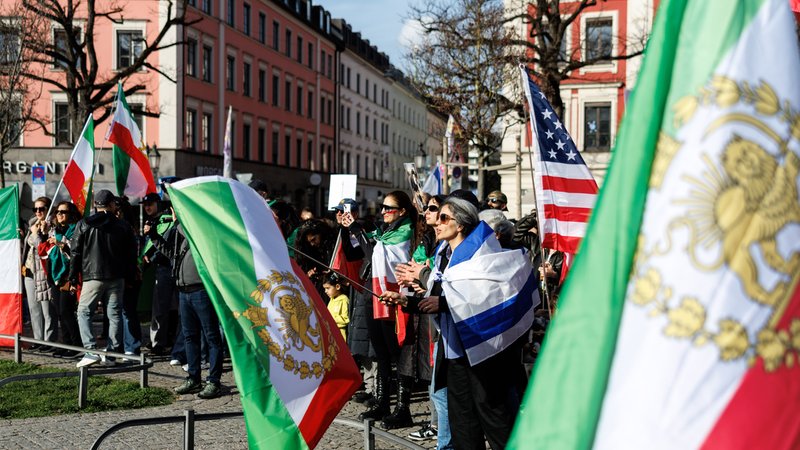 Teilnehmer einer Kundgebung unter dem Motto "Nein zur Islamischen Republik Iran!" mit Flaggen von den USA und vom Iran am Gärtnerplatz | Bild: picture alliance/dpa | Matthias Balk Teilnehmer einer Kundgebung unter dem Motto "Nein zur Islamischen Republik Iran!" mit Flaggen von den USA und vom Iran am Gärtnerplatz