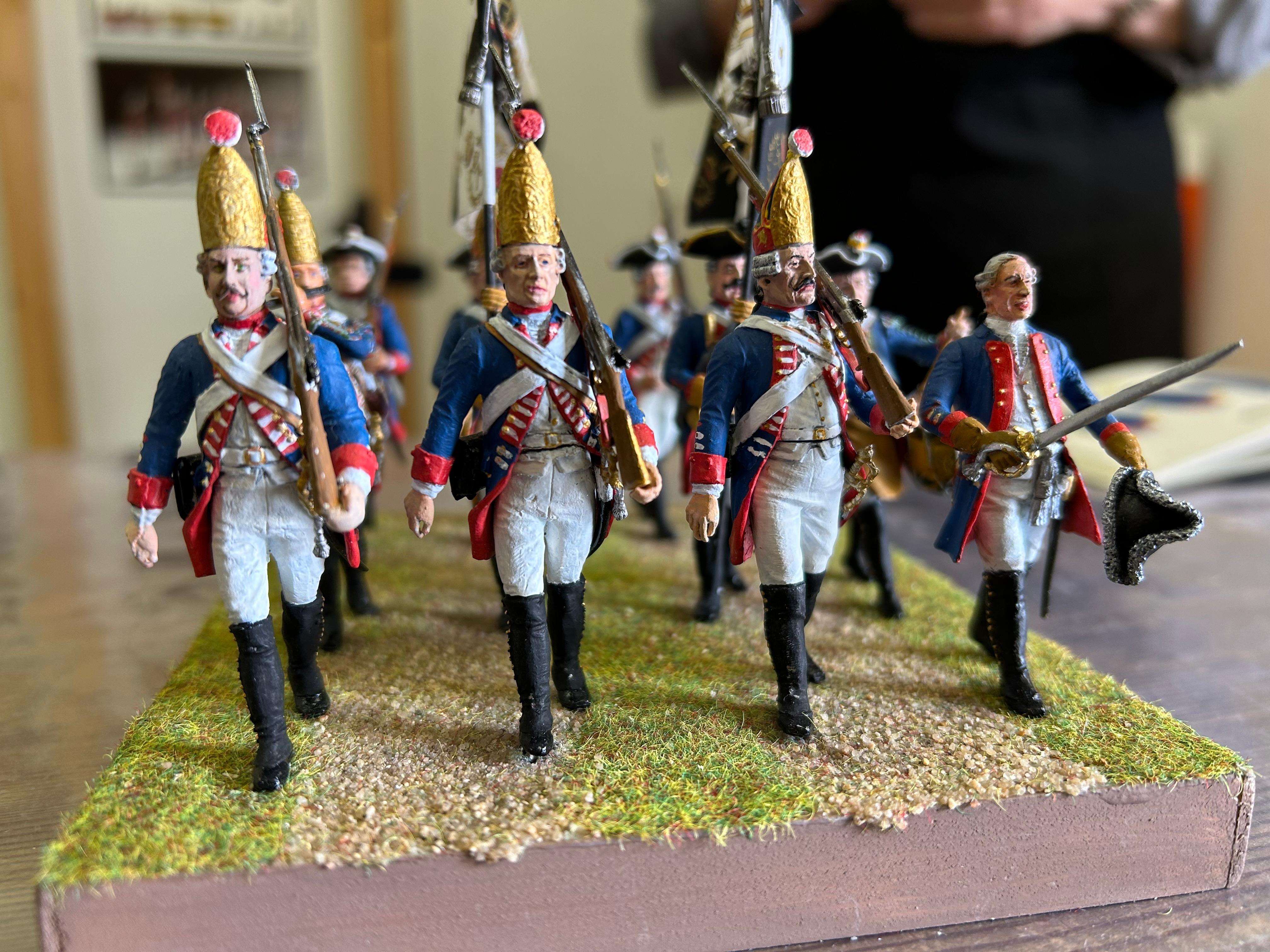 Mehrere Zinnsoldaten stehen auf einem Untergrund, der aussieht wie eine Wiese mit einem Feldweg.