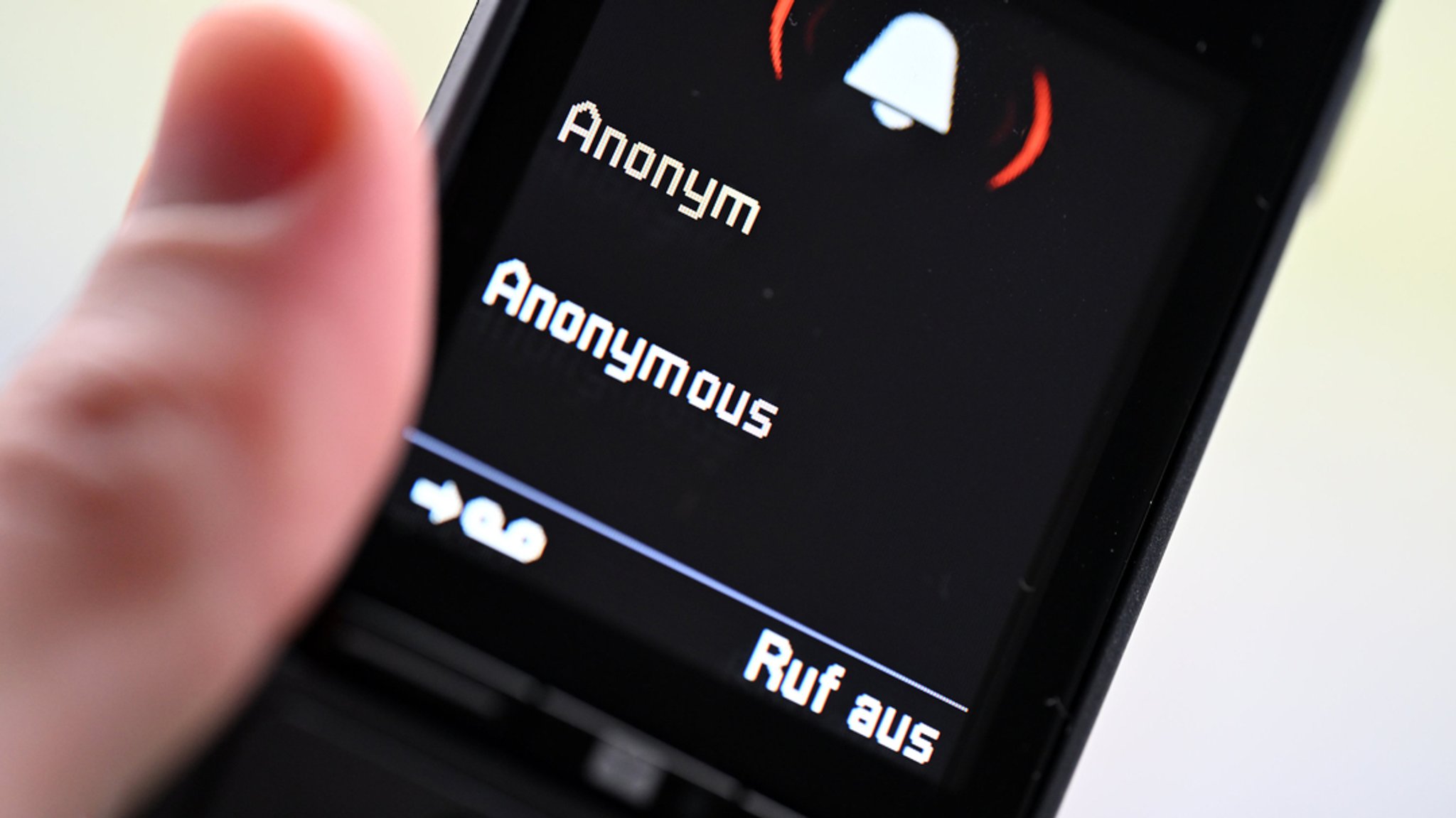 Ein Mann hält ein Festnetz-Telefon, auf dem ein anonymer Anruf eingeht.
