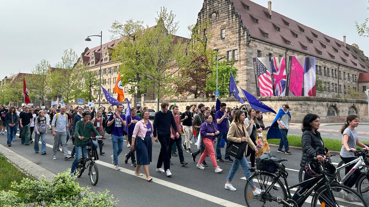 Menschen ziehen bei einer Demonstration vor dem Nürnberger Justizpalast vorbei.