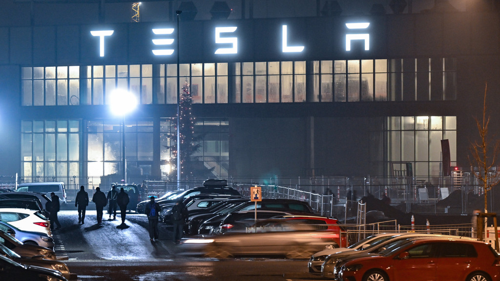 Grünheide: Mitarbeiter gehen am frühen Morgen auf einem Parkplatz zum Werk des US-Elektroautobauers Tesla