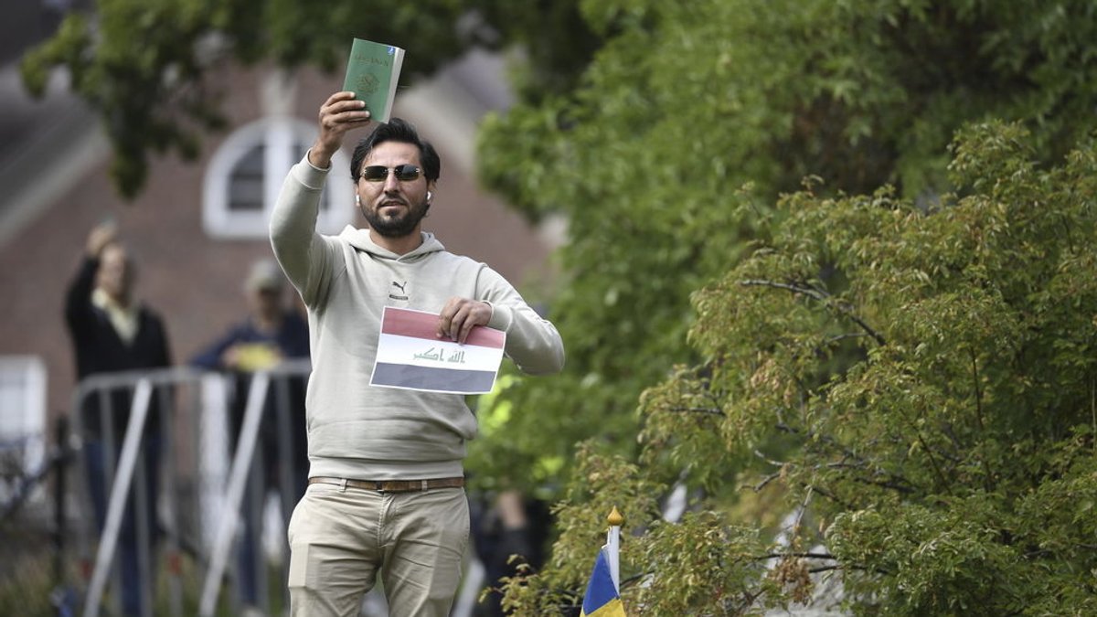 20.07.2023, Schweden, Stockholm: Salwan Momika, Demonstrant, hält eine Kopie des Korans, die er mutmaßlich gemeinsam mit einer irakischen Fahne vor der irakischen Botschaft verbrennen will. Foto: Oscar Olsson/TT NEWS AGENCY/AP/dpa +++ dpa-Bildfunk +++