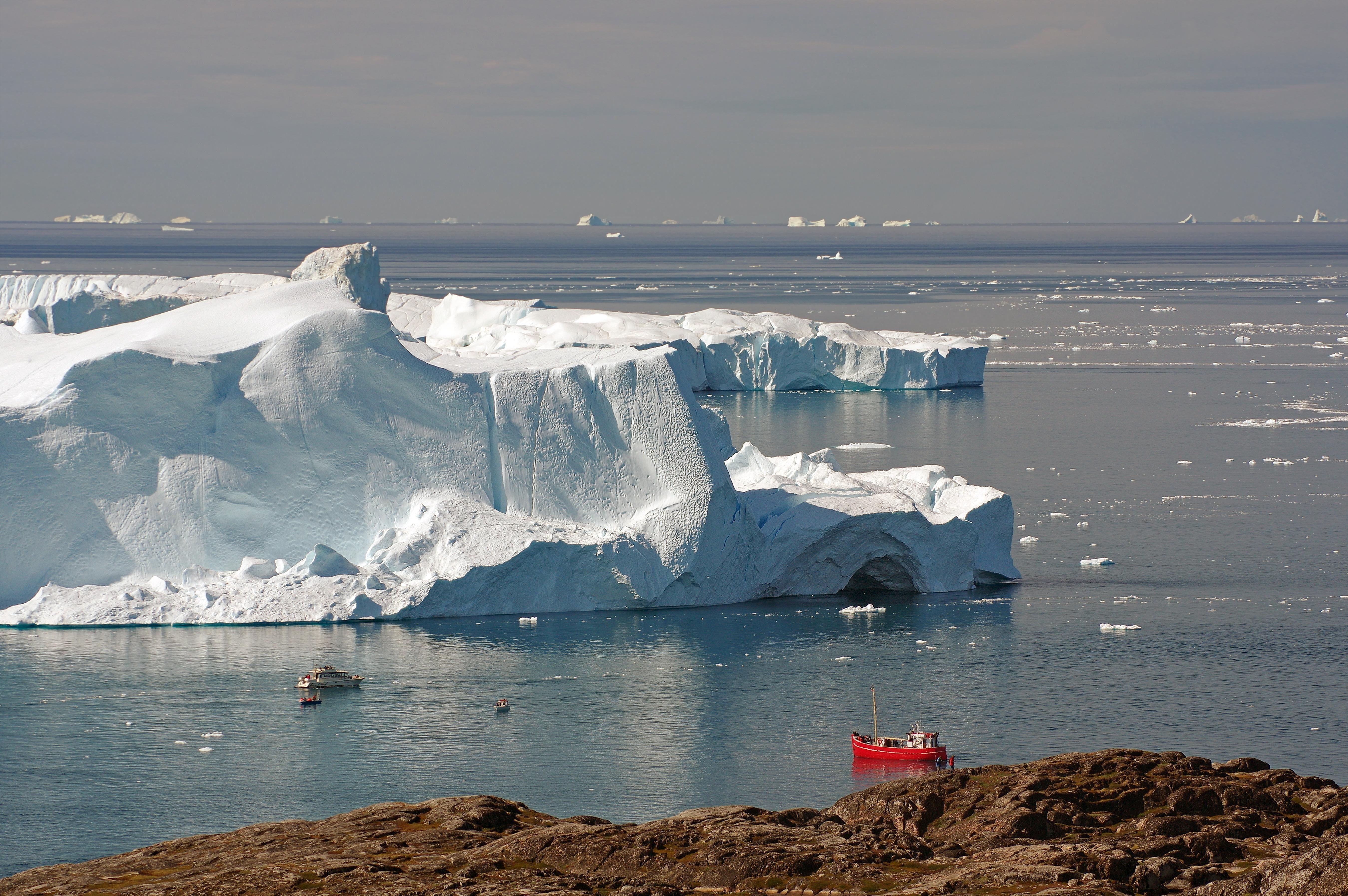 Aussicht auf rotes Boot vor riesigen Eisbergen, Diskobucht, Sermermuit, Ilulissat, Grönland