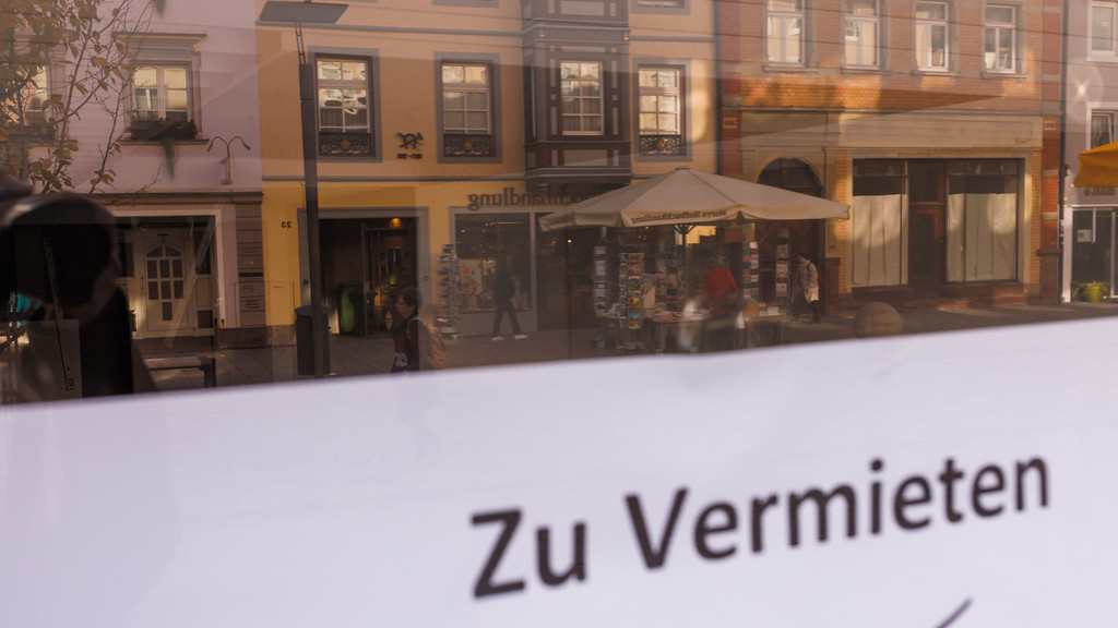 Ein Zettel mit der Aufschrift "Zu Vermieten" hängt am Fenster eines leerstehenden Ladengeschäfts während sich darin die Innenstadt von Villingen-Schwenningen spiegelt. 