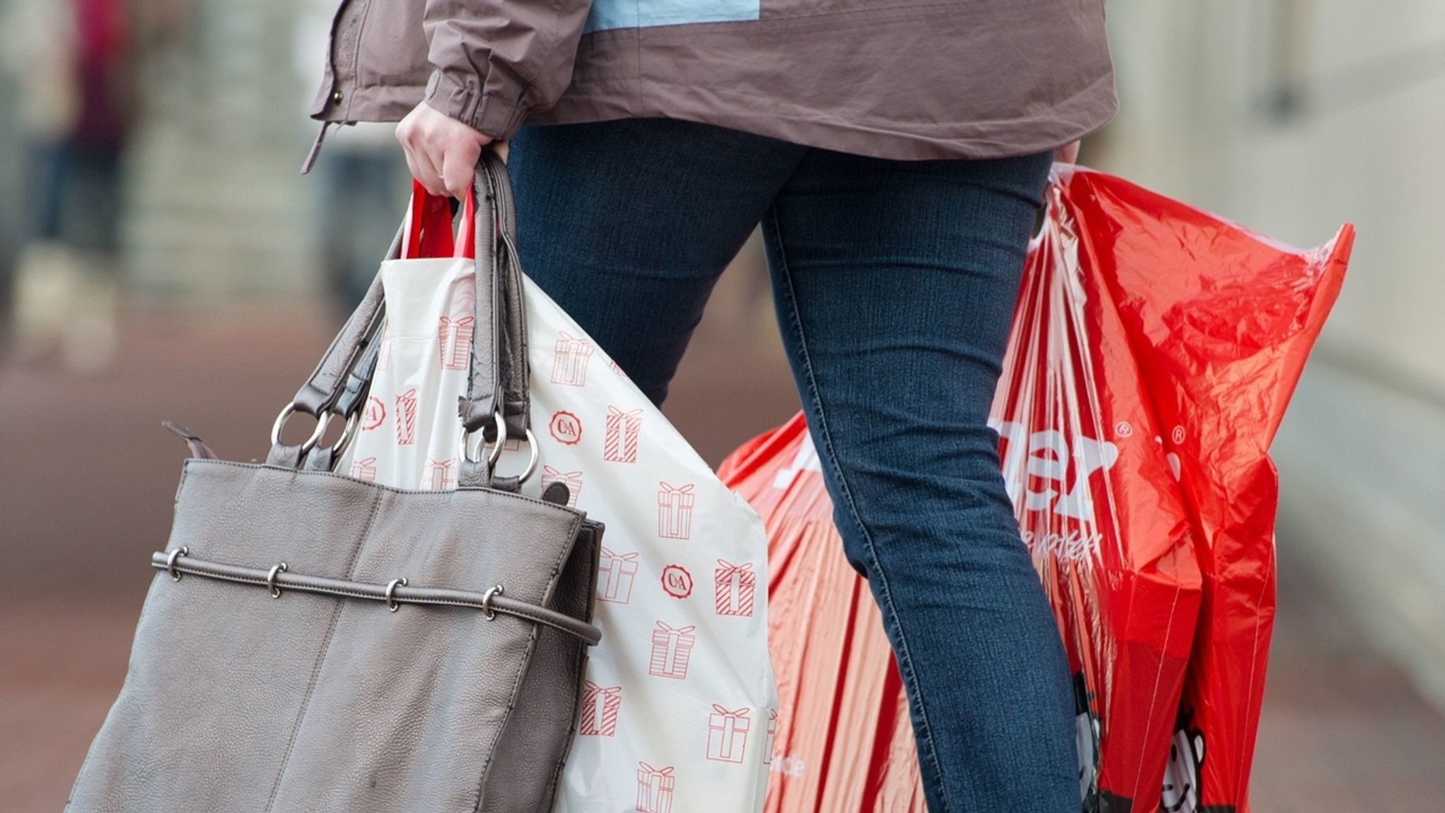 Frau trägt mehrere Einkaufstüten