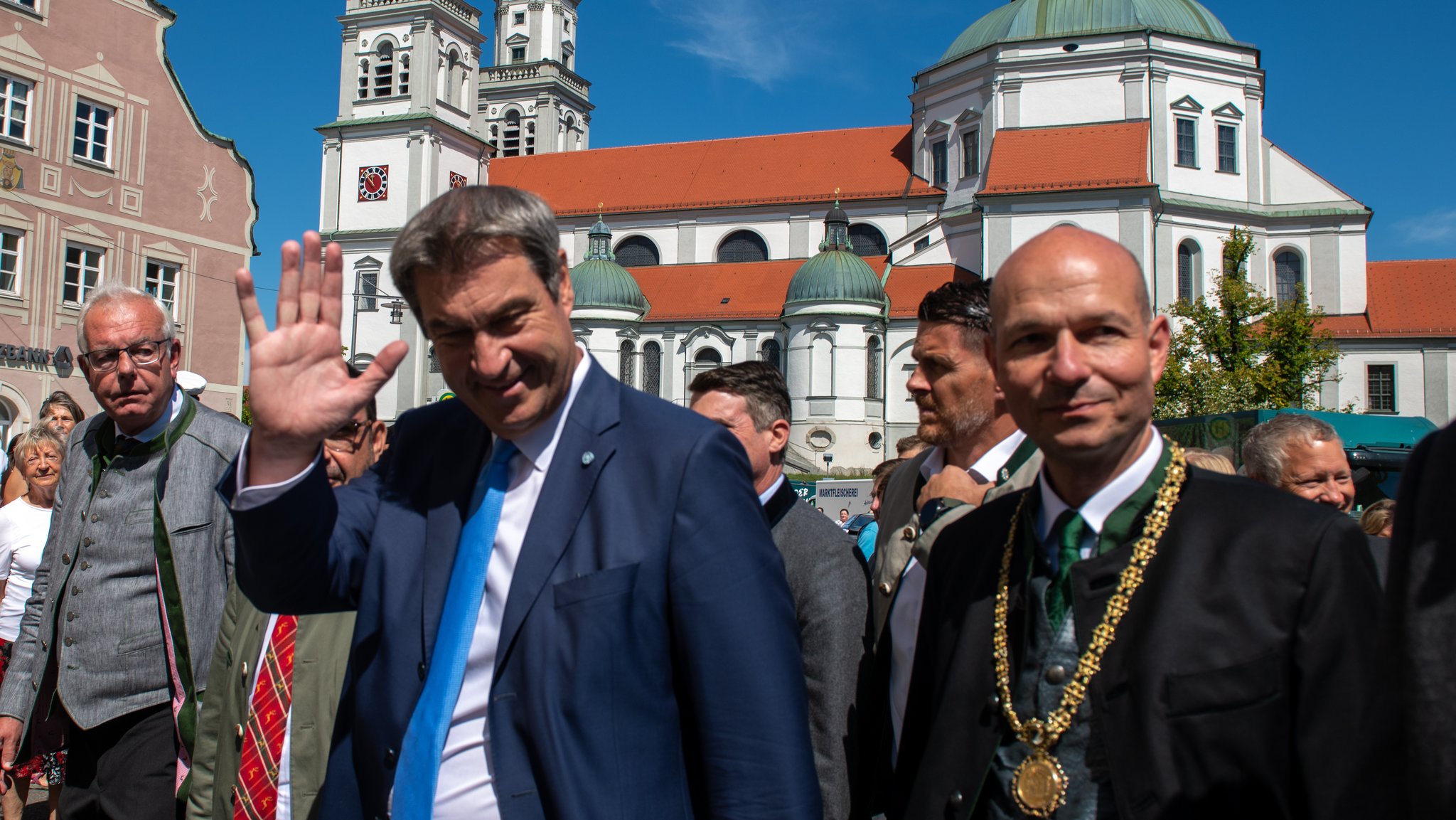 Markus Söder (CSU, M), Ministerpräsident von Bayern, winkt bei der Eröffnung der 71. Allgäuer Festwoche vor der Basilika Sankt Lorenz, links Thomas Kreuzer, Fraktionsvorsitzender der CSU im bayerischen Landtag, recht Thomas Kiechle (CSU), Oberbürgermeister von Kempten. Die Allgäuer Festwoche in Kempten gehörte vor der Pandemie zu den zehn größten Verbrauchermessen Deutschlands - mit mehr als 172 000 Besuchern im Jahr 2019. Die Wirtschaftsmesse wird in diesem Jahr kleiner ausfallen, Kulturtage und Heimatfest sind aber weiter Teil des Programms.