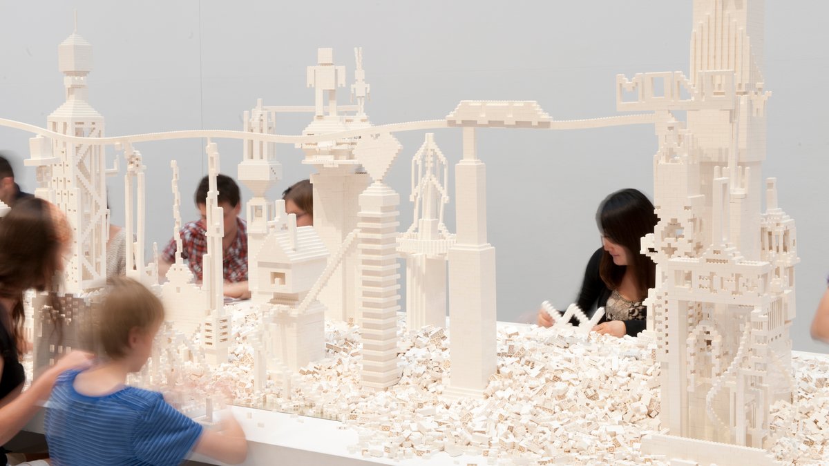 Kinder bauen mit weißen Legosteinen eine Stadt