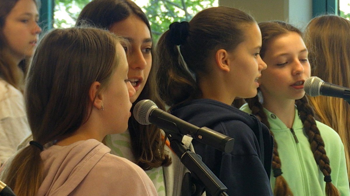 Schülerinnen singen in Mikrofone.