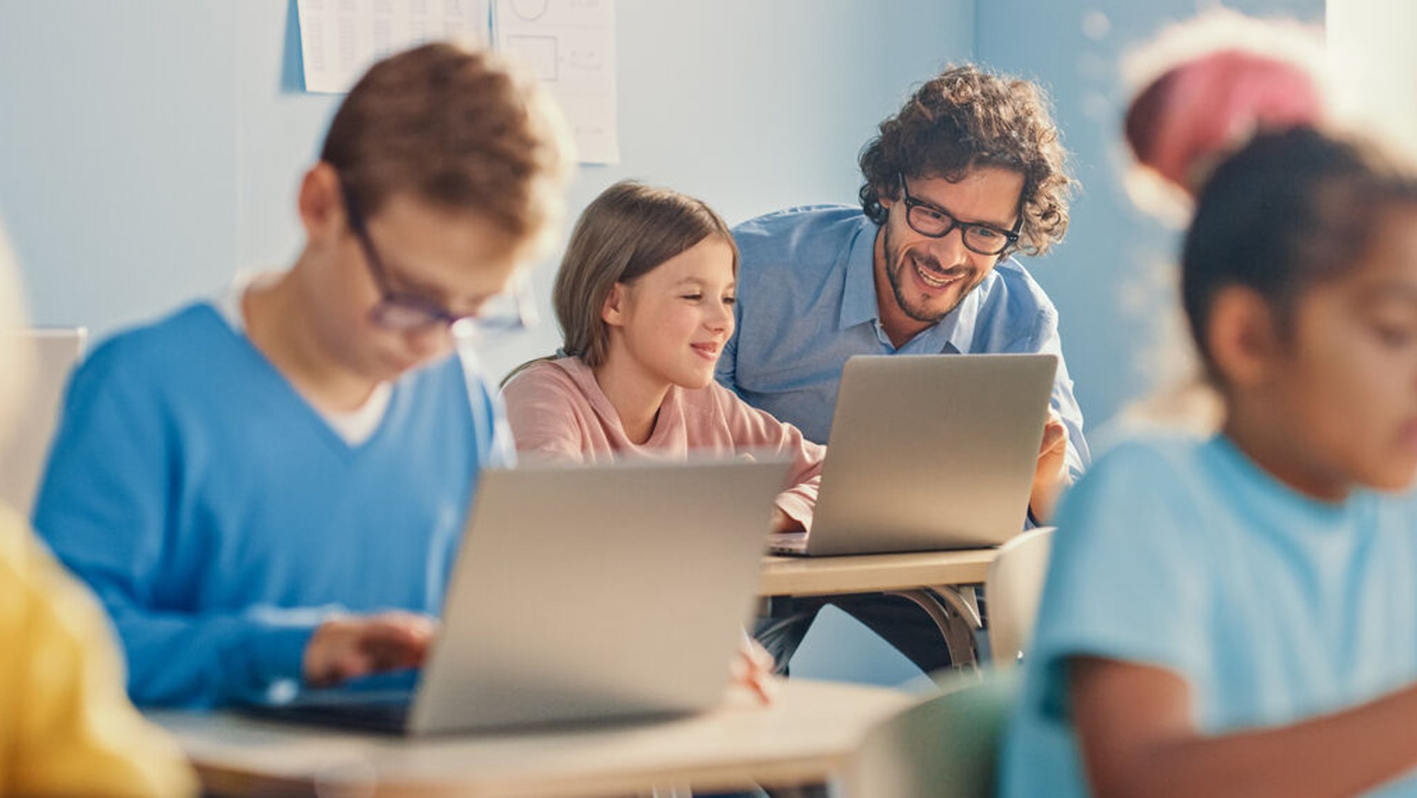 Ein Klassenlehrer erklärt einer Schülerin etwas am Laptop (Symbolbild).