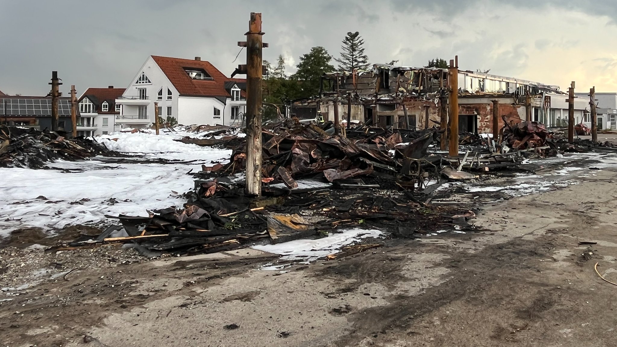 Am Morgen nach dem Brand bedeckt weißer Löschschaum große Teile der Brandruine. Vom früheren Autohaus ist nicht viel übrig geblieben.