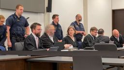 Die Angeklagten mit ihren Verteidigern im Gerichtssaal, im Hintergrund Justizbeamte. | Bild:BR24/Henry Lai
