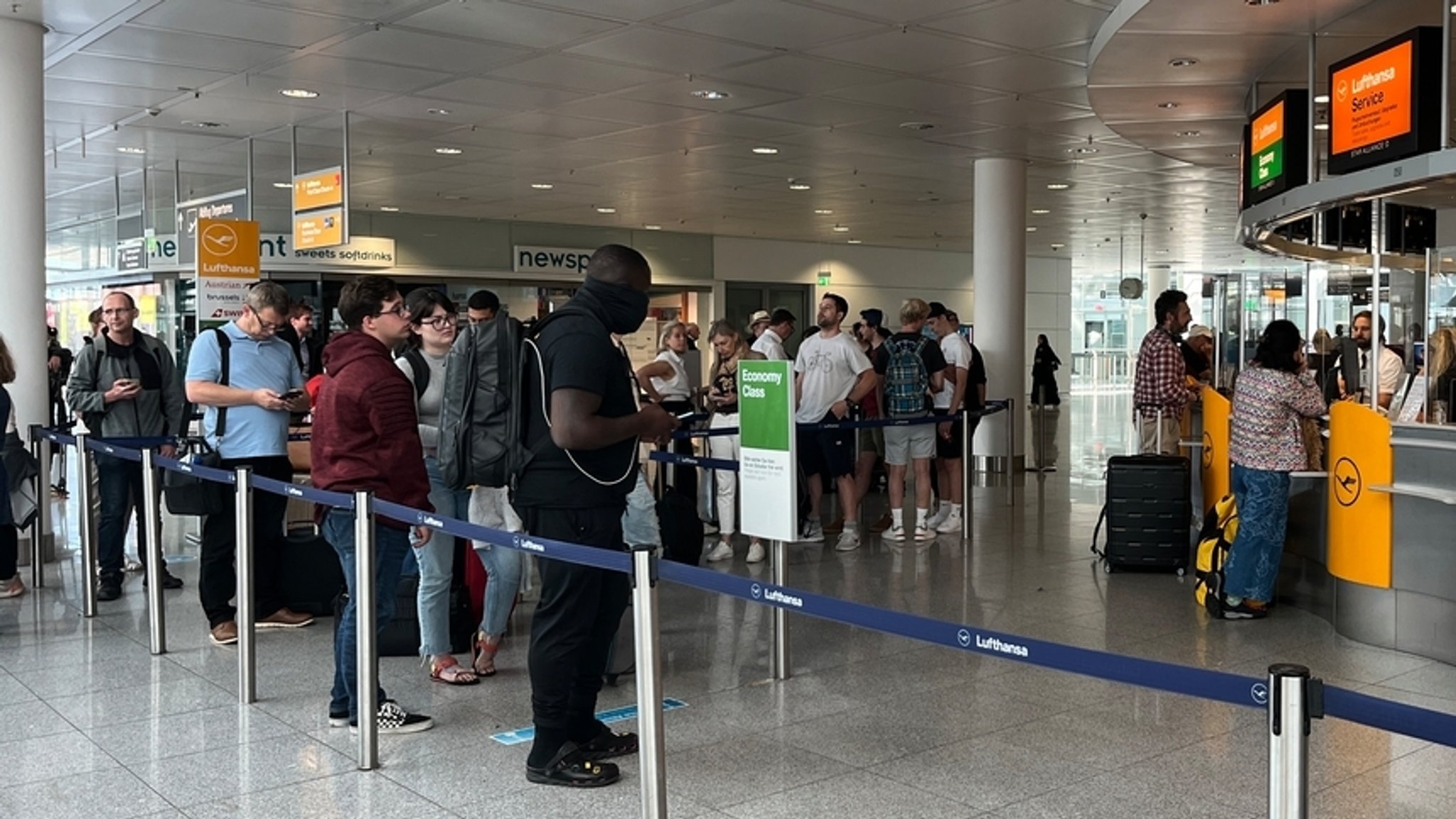 Flugpassagiere stehen in einer Schlange am Check-In-Schalter an.