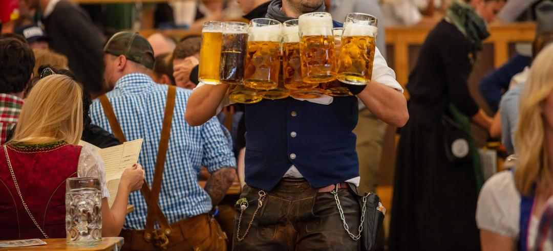 Ein Kellner trägt gefüllte Maßkrüge in einem Festzelt auf dem Münchner Oktoberfest aus.