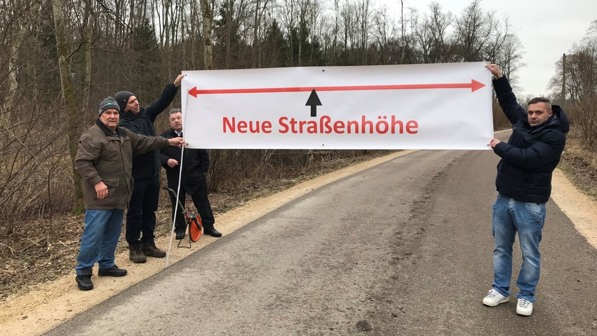 Bund Naturschutz und Mitglieder der Bürgerinitiative wollen Autofahrer mit einem Transparent auf die neue Höhe der Fahrbahn nach dem Straßenausbau hinweisen.