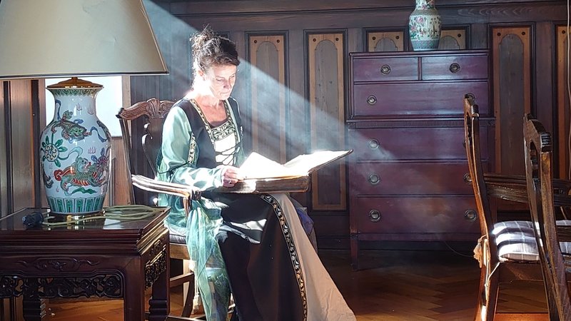 Schlossherrin Sandra de Greef blättert in einem dicken Buch mit alten Sagen.