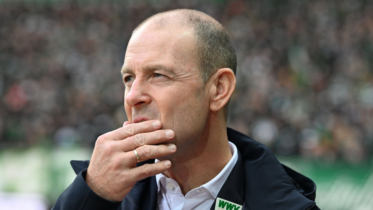 Der Trainer vom FC Augsburg fasst sich an den Mund und blickt kritisch.