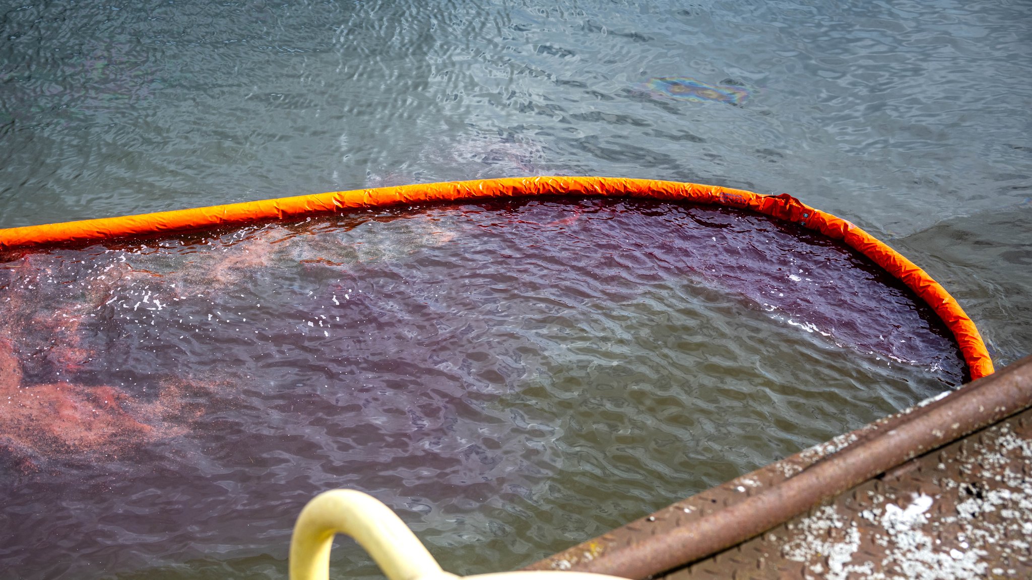 Treibstoff mischt sich mit Wasser an einer Ölsperre.