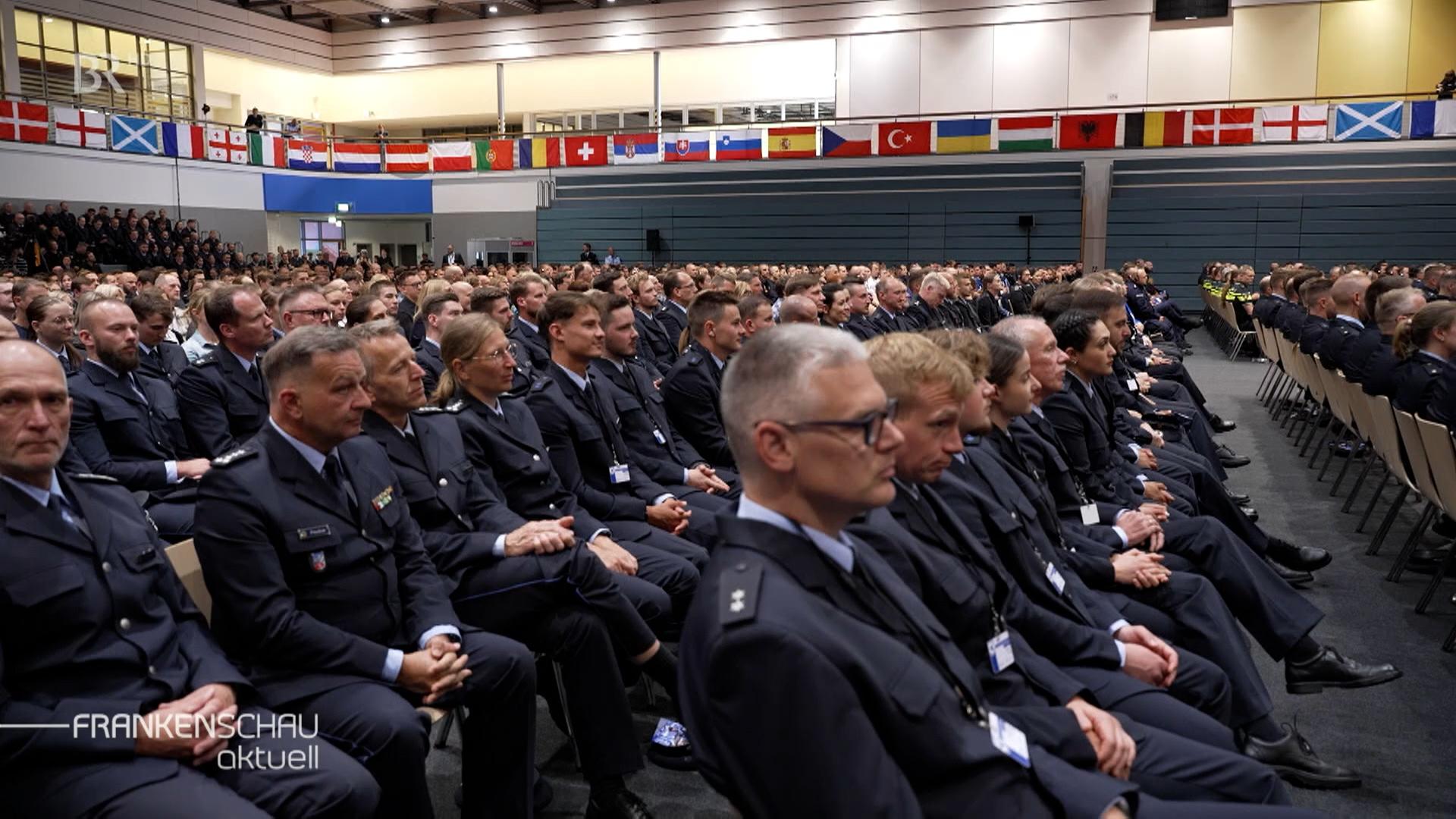 Mehrere Polizeibeamt:innen sitzen in einem Saal.