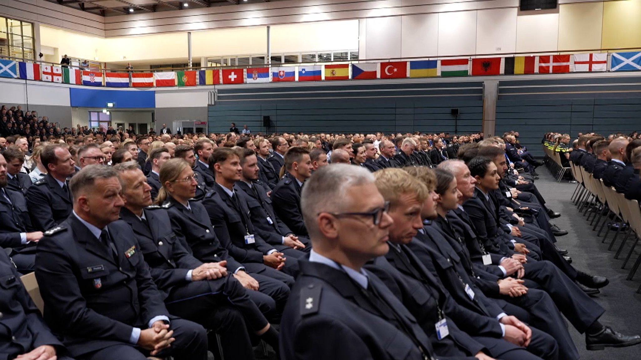 Mehrere Polizeibeamt:innen sitzen in einem Saal.