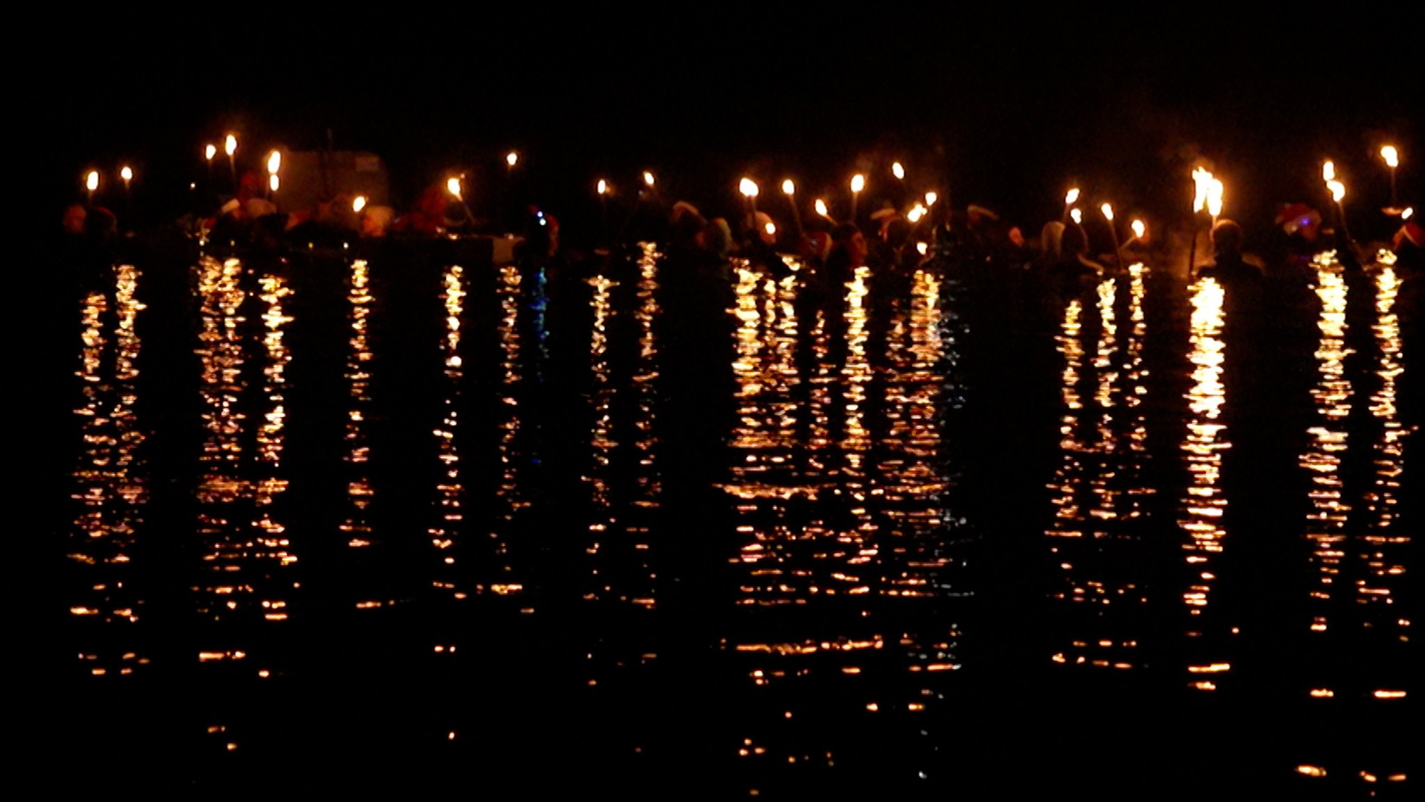 Schwimmer mit Fackeln spiegeln sich im Wasser der Donau