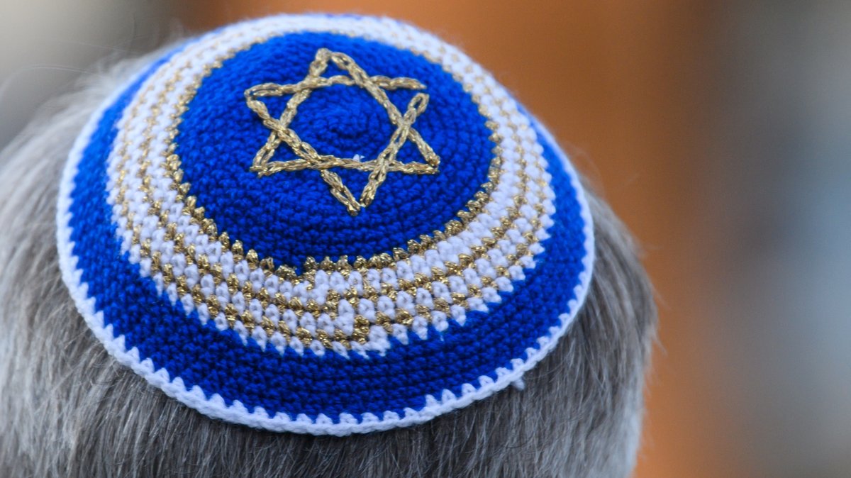 Ein Mann trägt im Rahmen einer Kranzniederlegung vor der Synagoge eine Kippa mit Judenstern - aufgenommen im November 2021. 