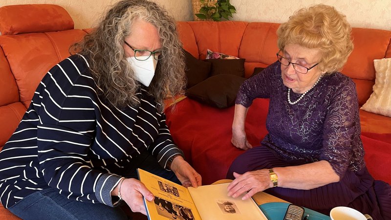 Alltagsbegleiterin Claudia Fichtner schaut mit Seniorin Anneliese Gumpp ein Fotoalbum an. 