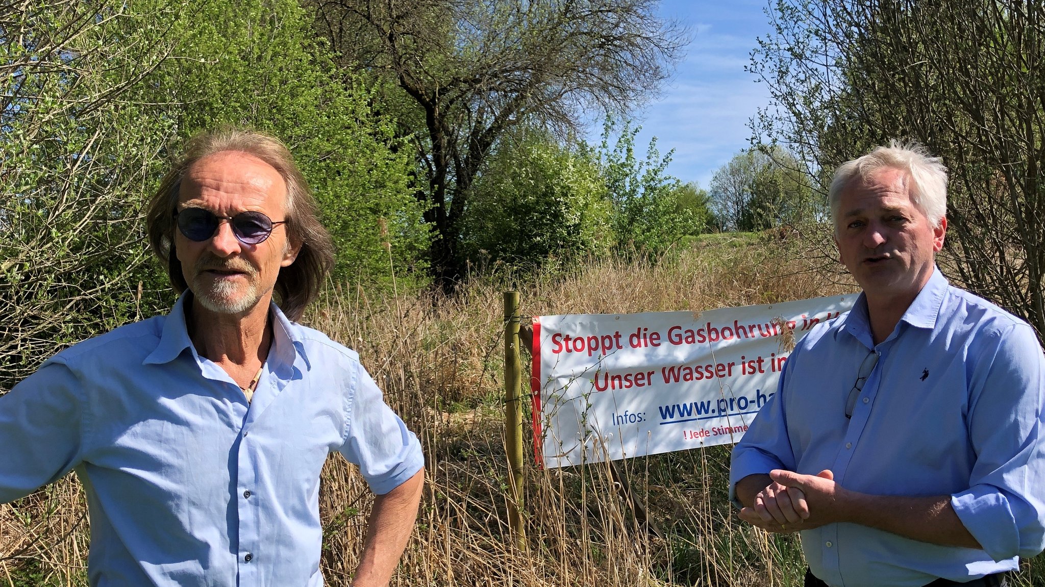 Schauspieler Eisi Gulp und Helmut Dörner vor einem Plakat der Bürgerinitiative "Pro Halfing"