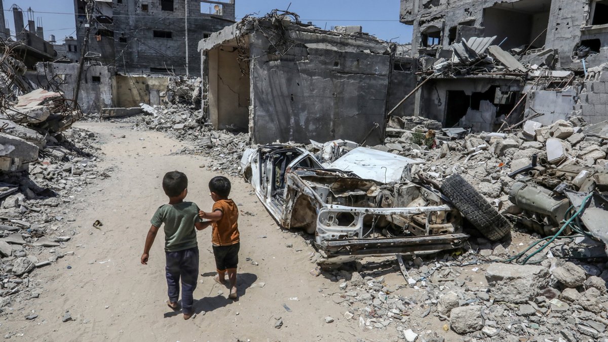 Kinder gehen nach einem israelischen Luftangriff neben zerstörten Gebäuden.