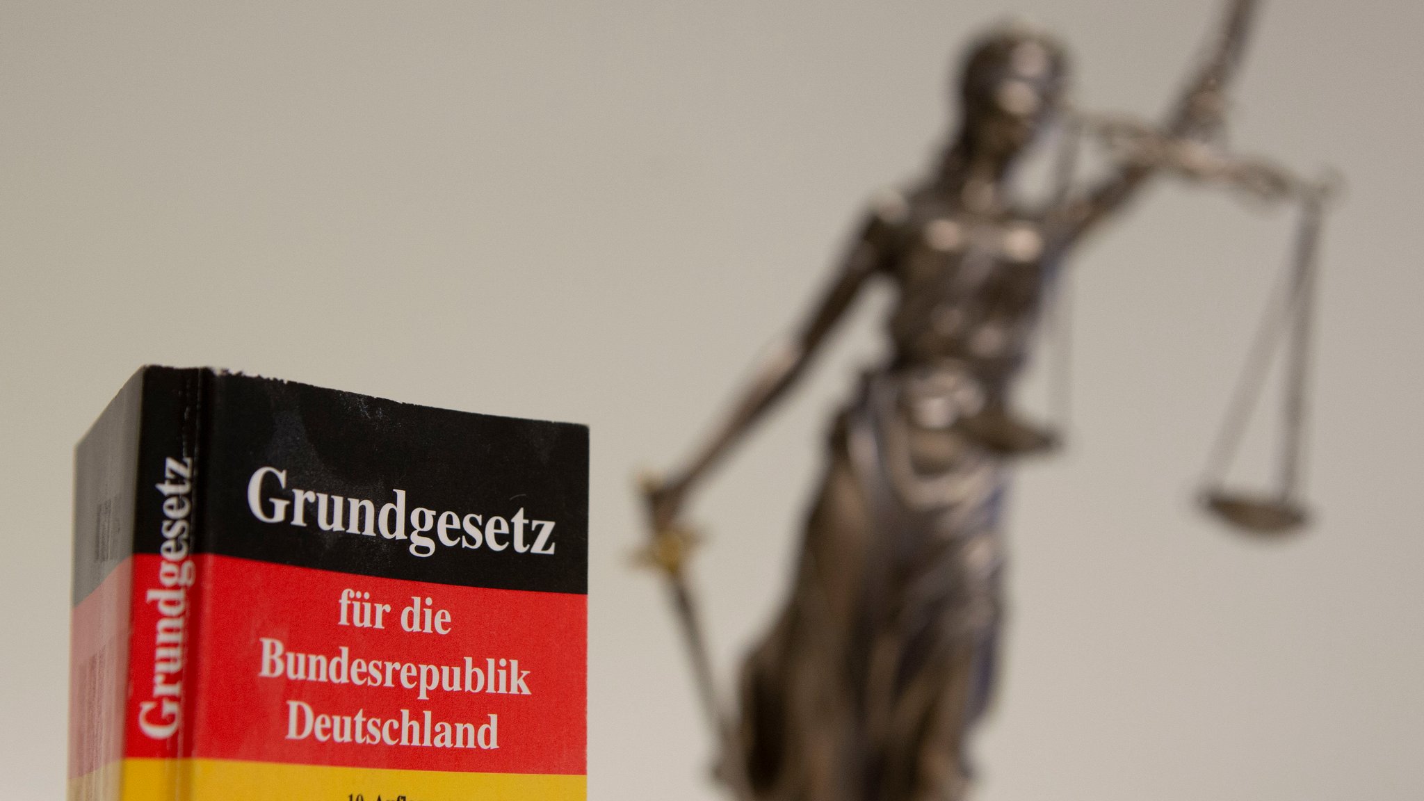 Grundgesetz mit Justitia-Figur im Hintergrund