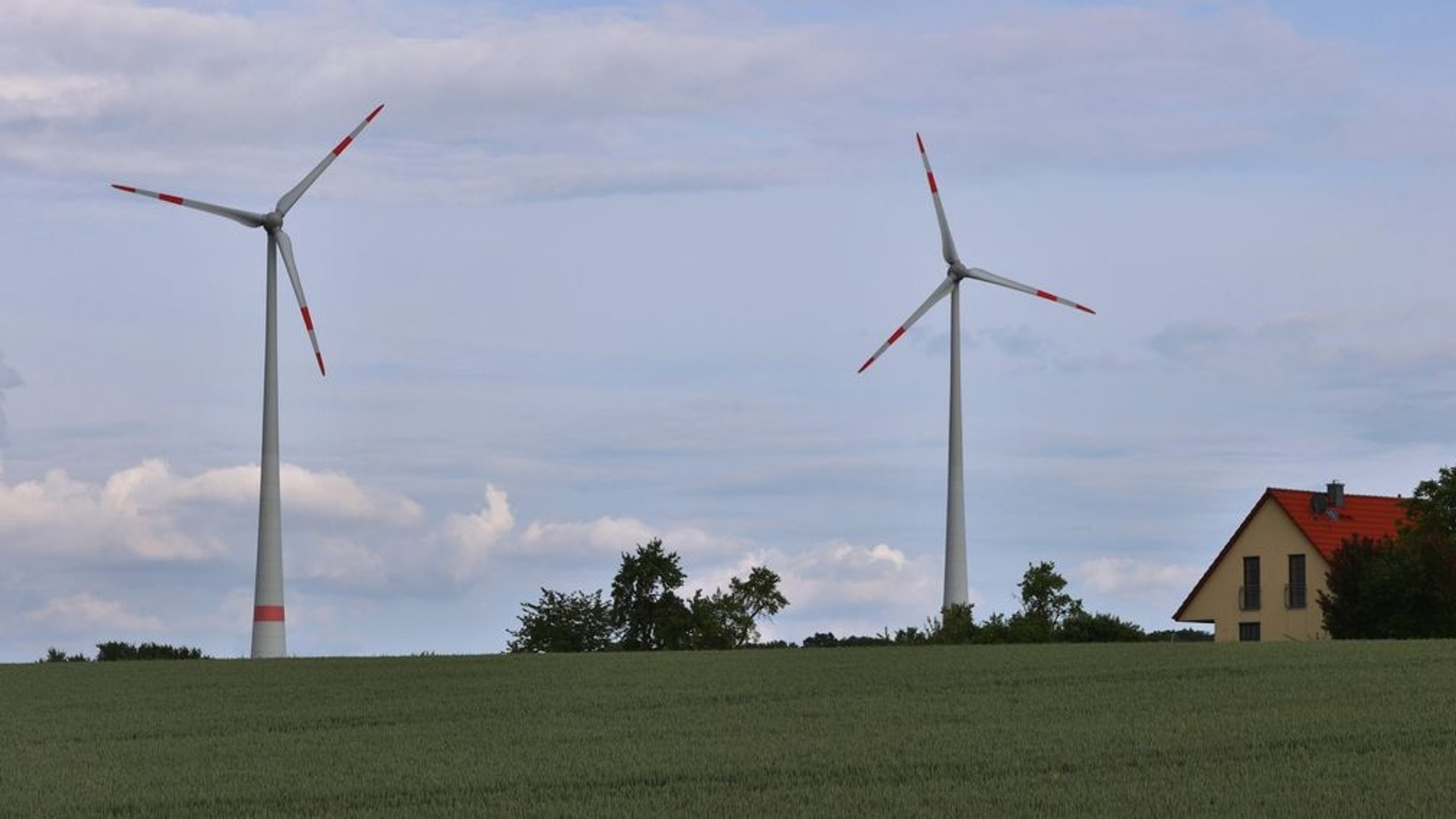 Windräder vor einem Haus in Bergtheim (Lkr. Würzburg). Nach dem Wegfall der 10H-Regel auf Bundesebene könnte der Windpark noch ausgebaut werden. 