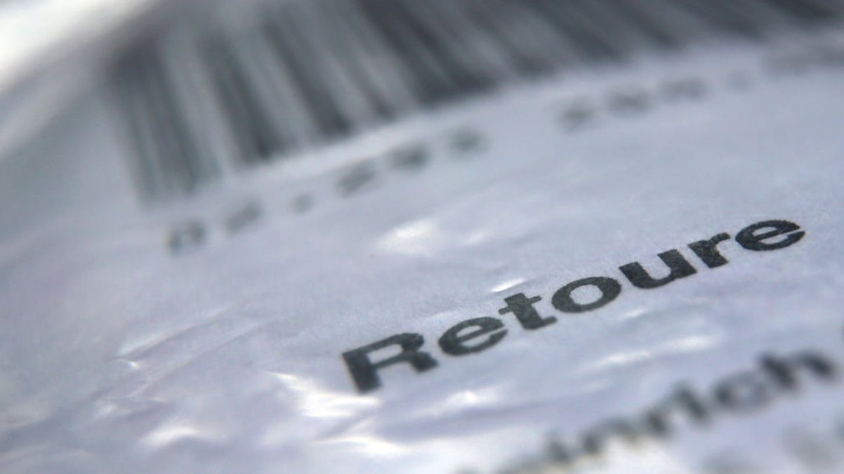 Das Wort "Retoure" steht auf dem Retourenaufkleber eines in Folie verpackten Päckchens, welches an einen Online-Versandhändler zurückgeschickt werden soll.