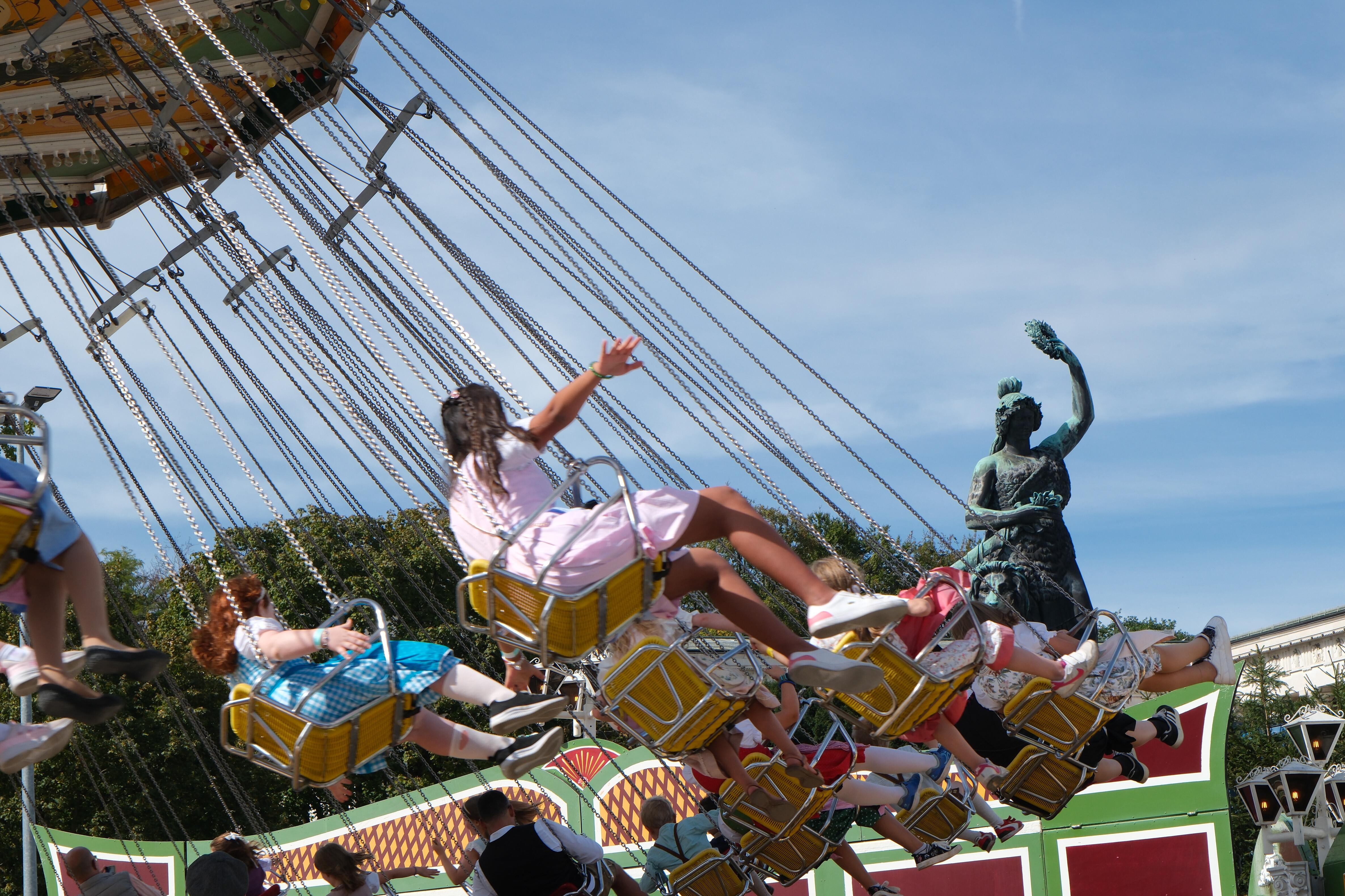 Menschen im Kettenkarussell, im Hintergrund die Bavaria-Statue auf der Theresienwiese. Schönes Wetter, viele Gäste, wenige Probleme: So lief das erste Wiesn-Wochenende. | Bild:picture alliance / ZUMAPRESS.com | Julius Mortsi