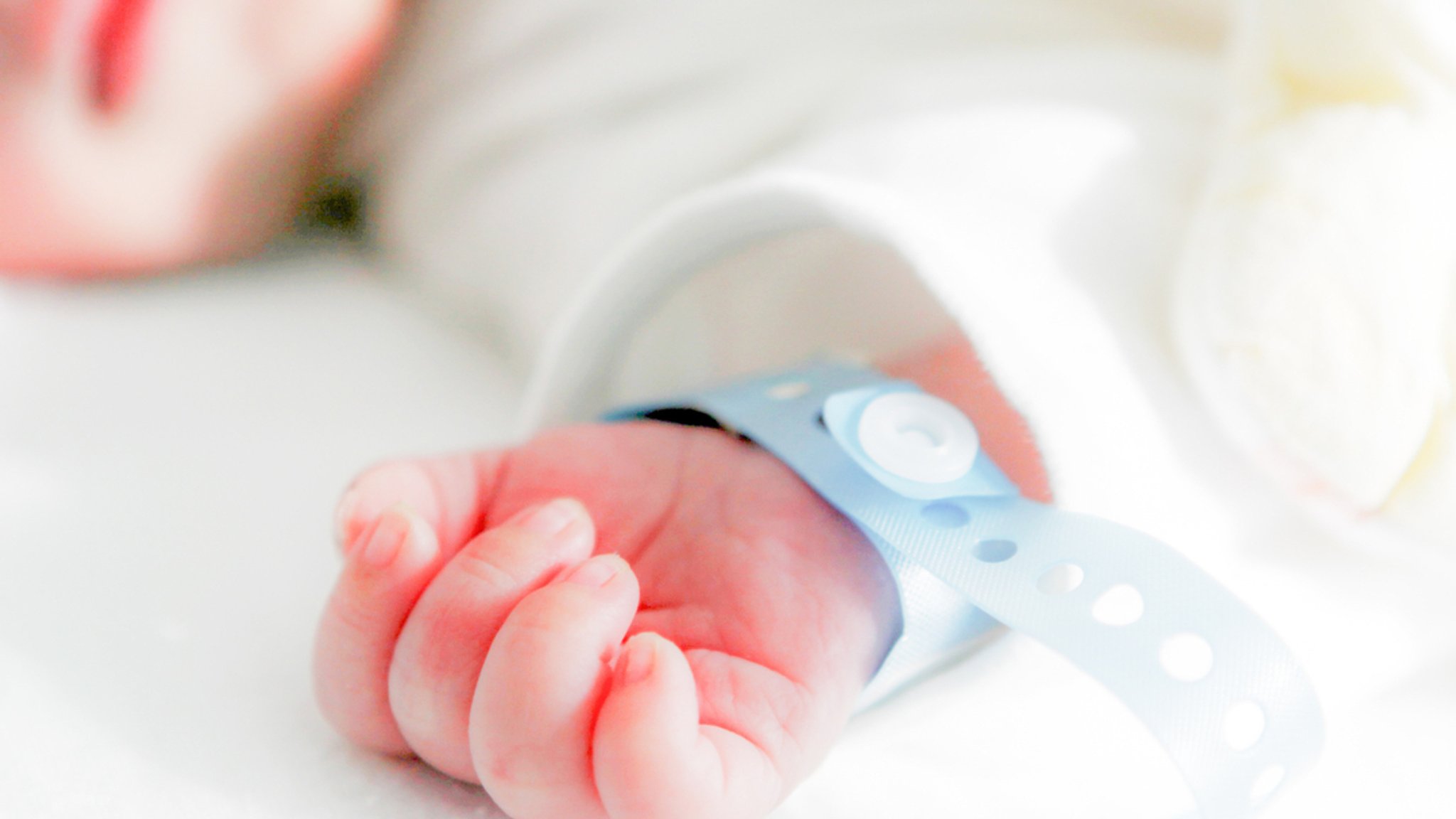 Symbolbild: Die Hand eines neugeborenen Babys mit Namensbändchen am Handgelenk.