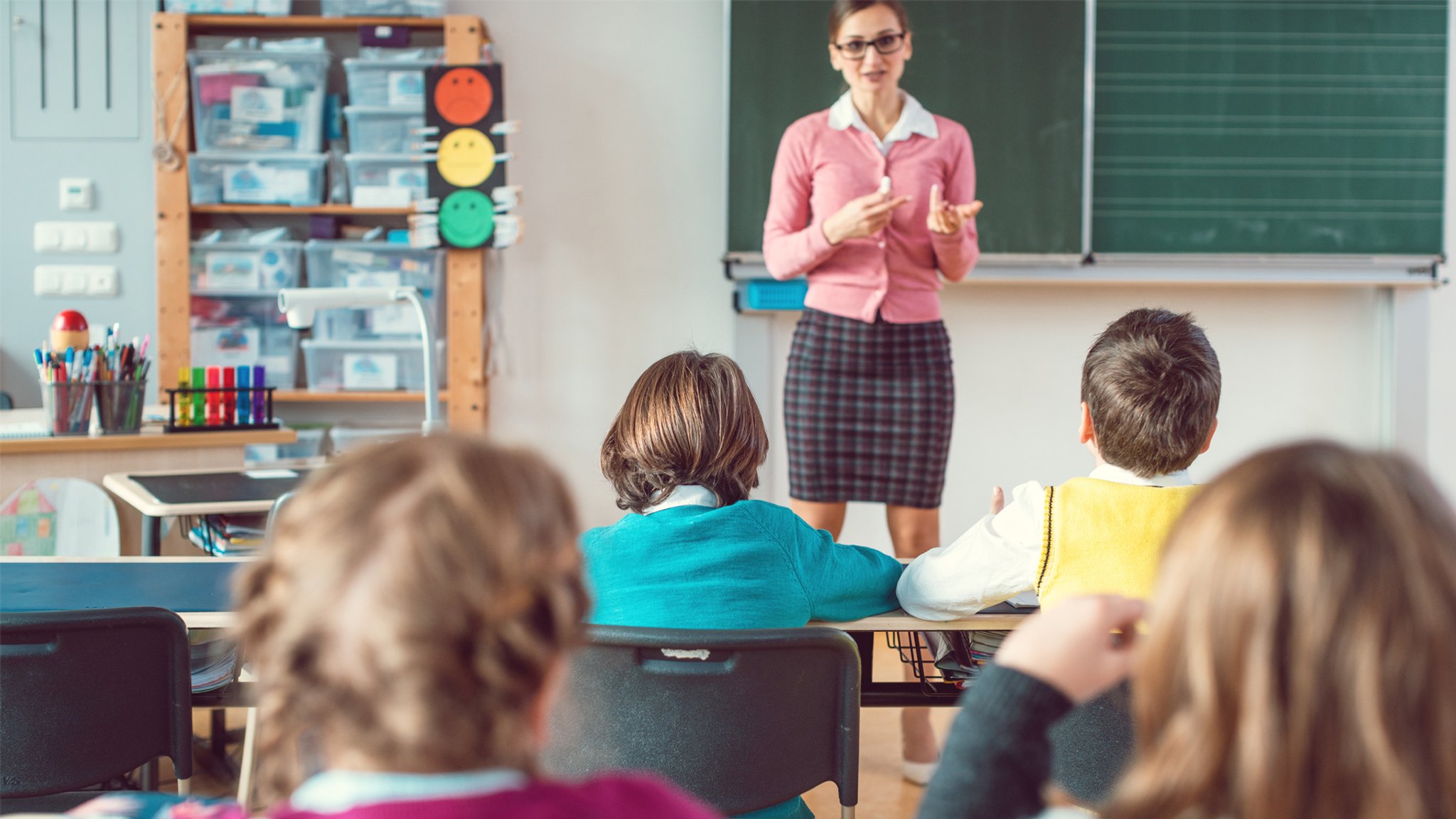 Lehrerin im Unterricht vor Tafel stehend